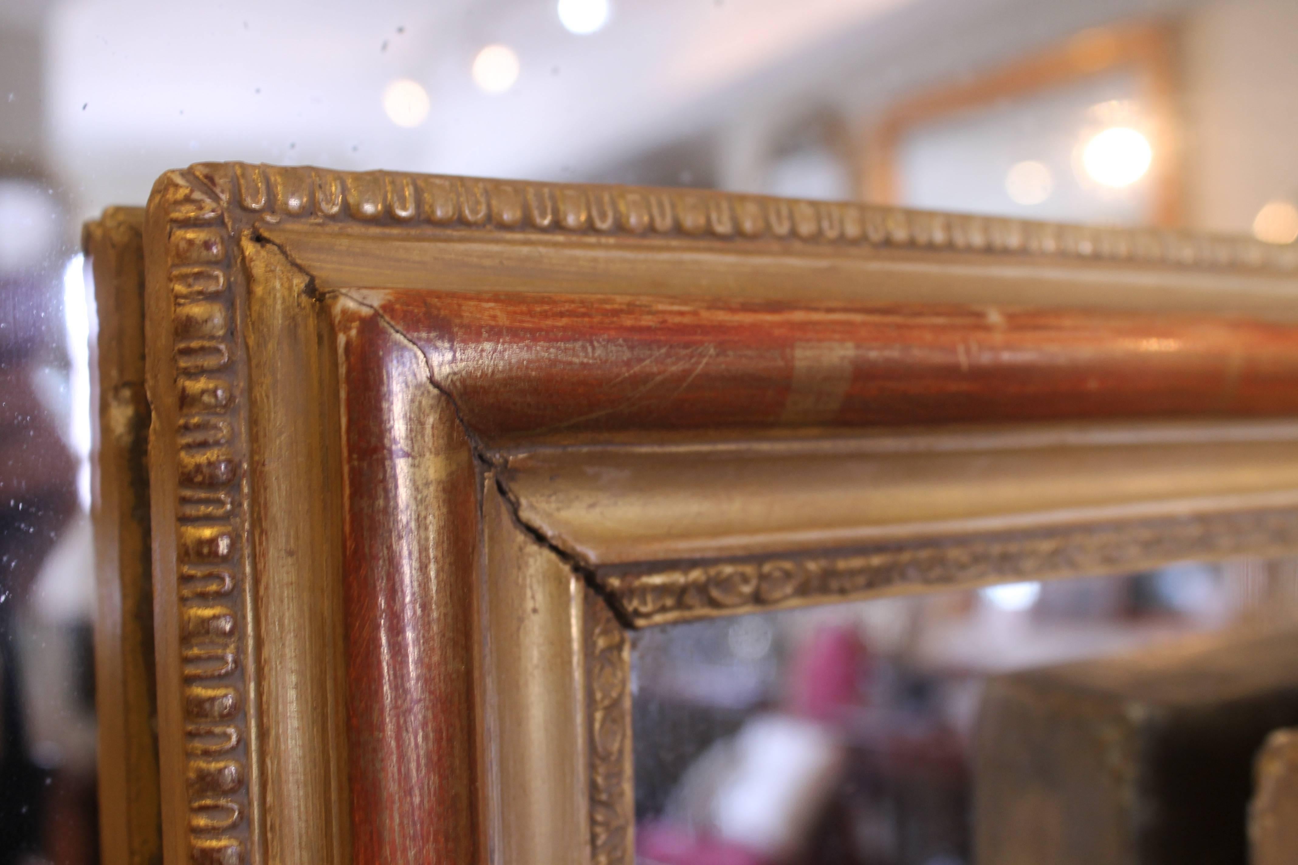 An excellent French mirror of useful size with good proportions to the design. The gilding has a pleasant evenly worn appearance with fine quality applied composition castings to the front and back edges, with a lovely warm, worn main burnished