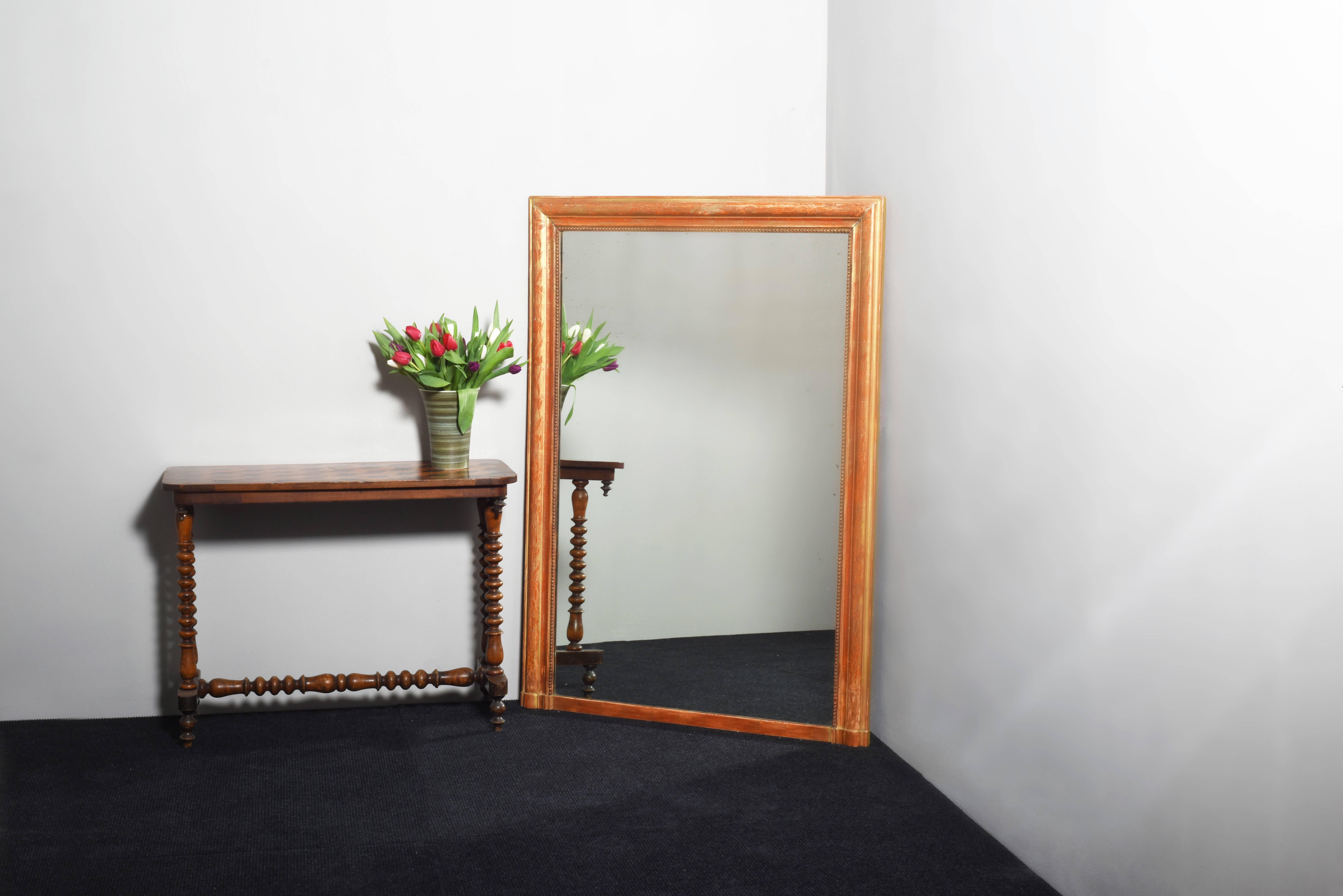 An attractive French mirror with a continual incised floral white cut design to the main section. The mirror has an attractive worn appearance, showing a fair amount of original red or orange under color, giving the gilding an attractive and rich