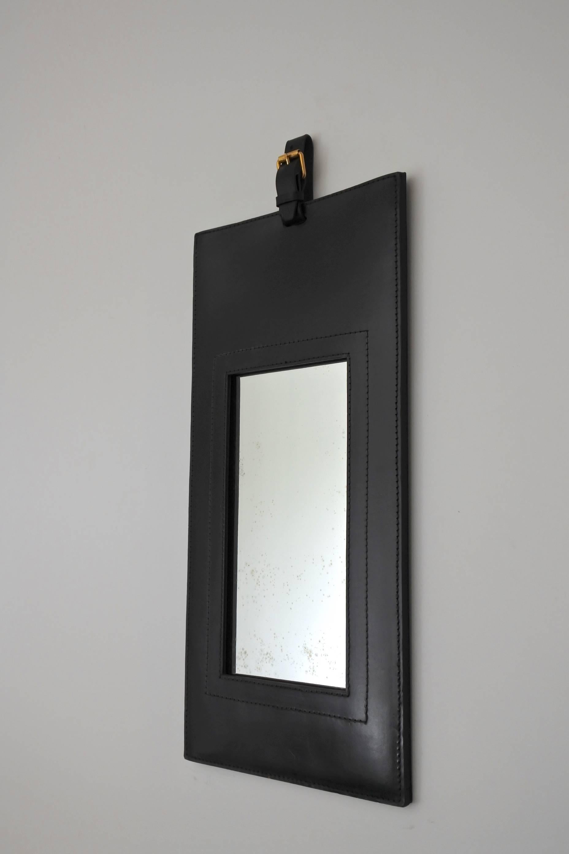 Midcentury hand stitched black leather and brass wall mirror in the manner of Jacques Adnet.
Made in France, circa 1950.
The glass shows oxydation marks due to age.