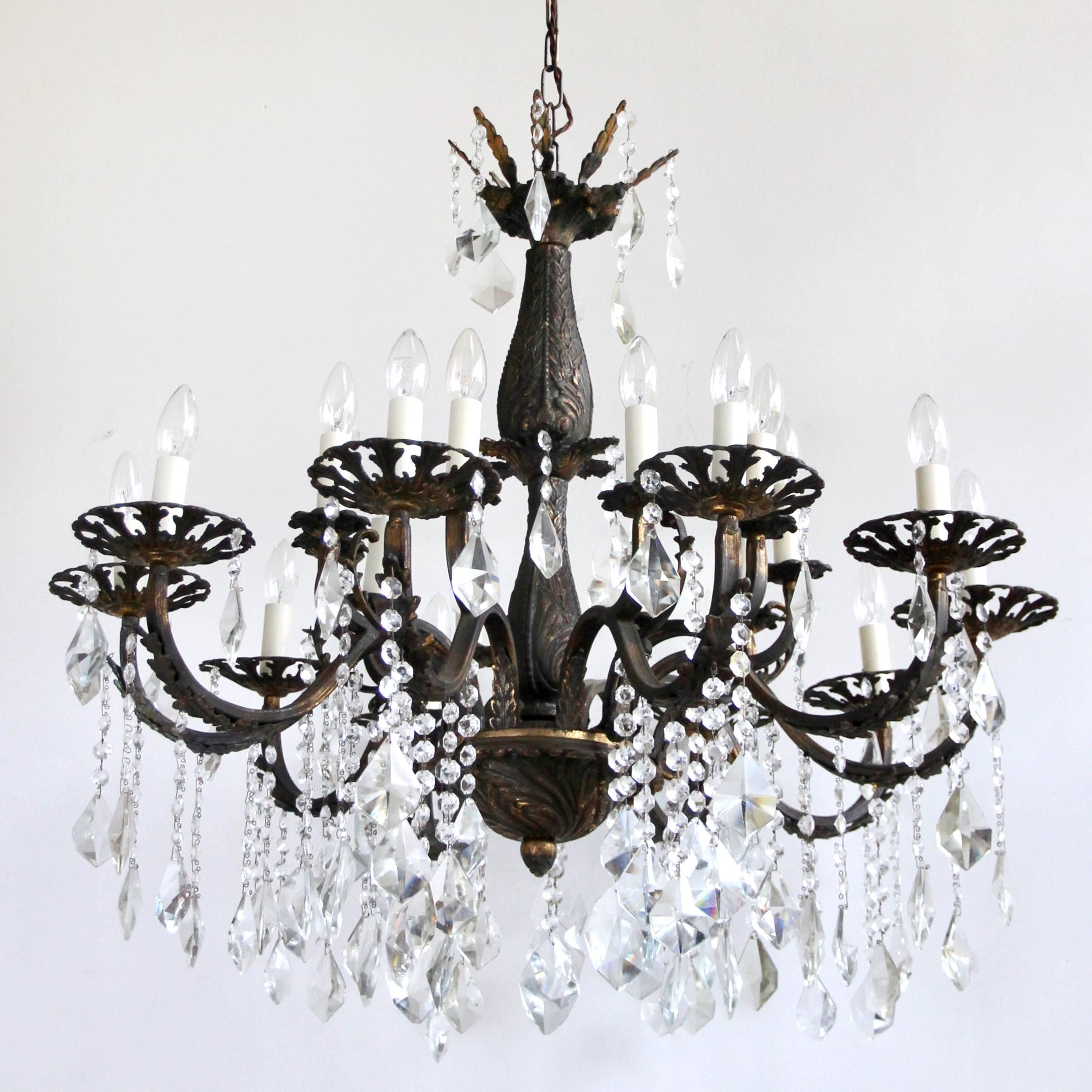 This large ornate brass chandelier has twenty lamps and dates from early 1900s, France. Its heavy cast brass frame has oxidised over time. We have taken care to leave this natural aged patina when restoring the piece. Dressed in strings of glass