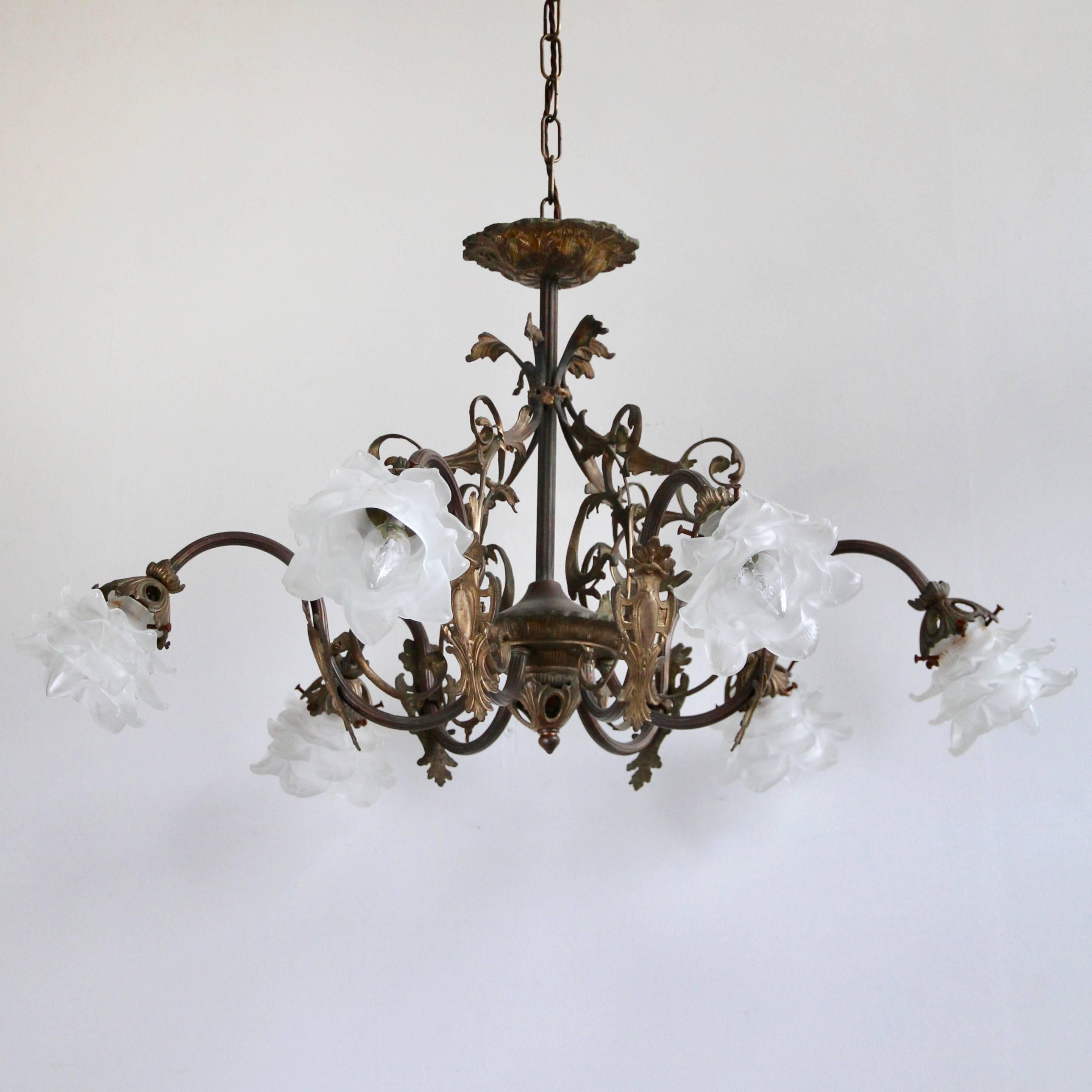 Decorative brass downlighter chandelier with frosted floral shades. The 1920s chandelier originates from France. The brass work is decorative and ornate. It has been sympathetically restored to retain the beautiful patina that has developed over