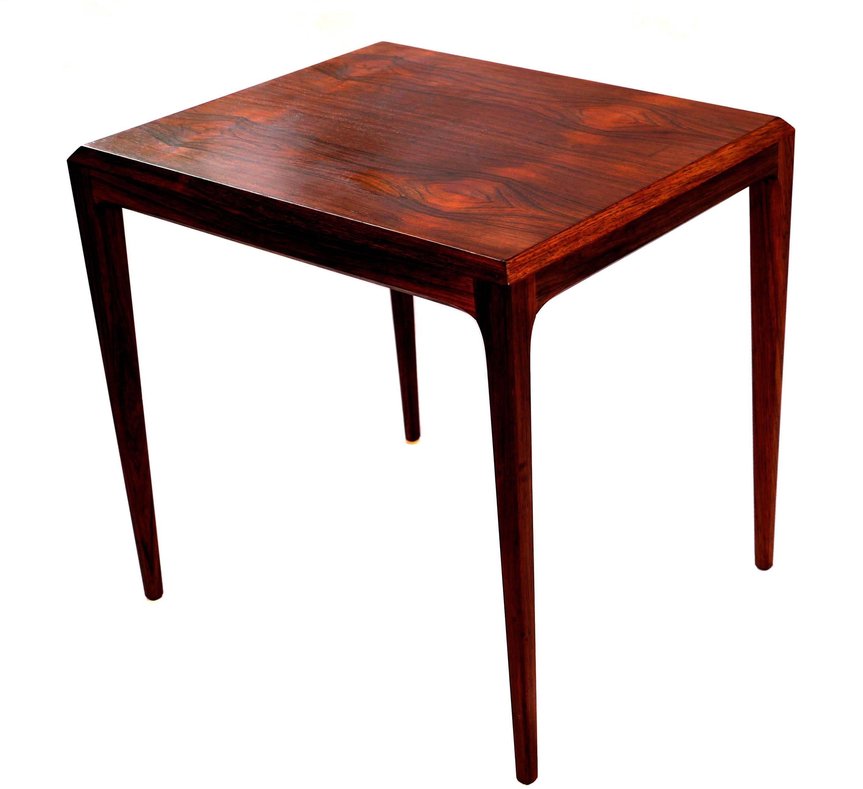 This side table was created by the Danish designer Johannes Andersen for CFC Silkeborg in Denmark. It consists of a rosewood veneered top and a solid rosewood frame. The design features slanted edges and cylindrical legs. Very good original vintage