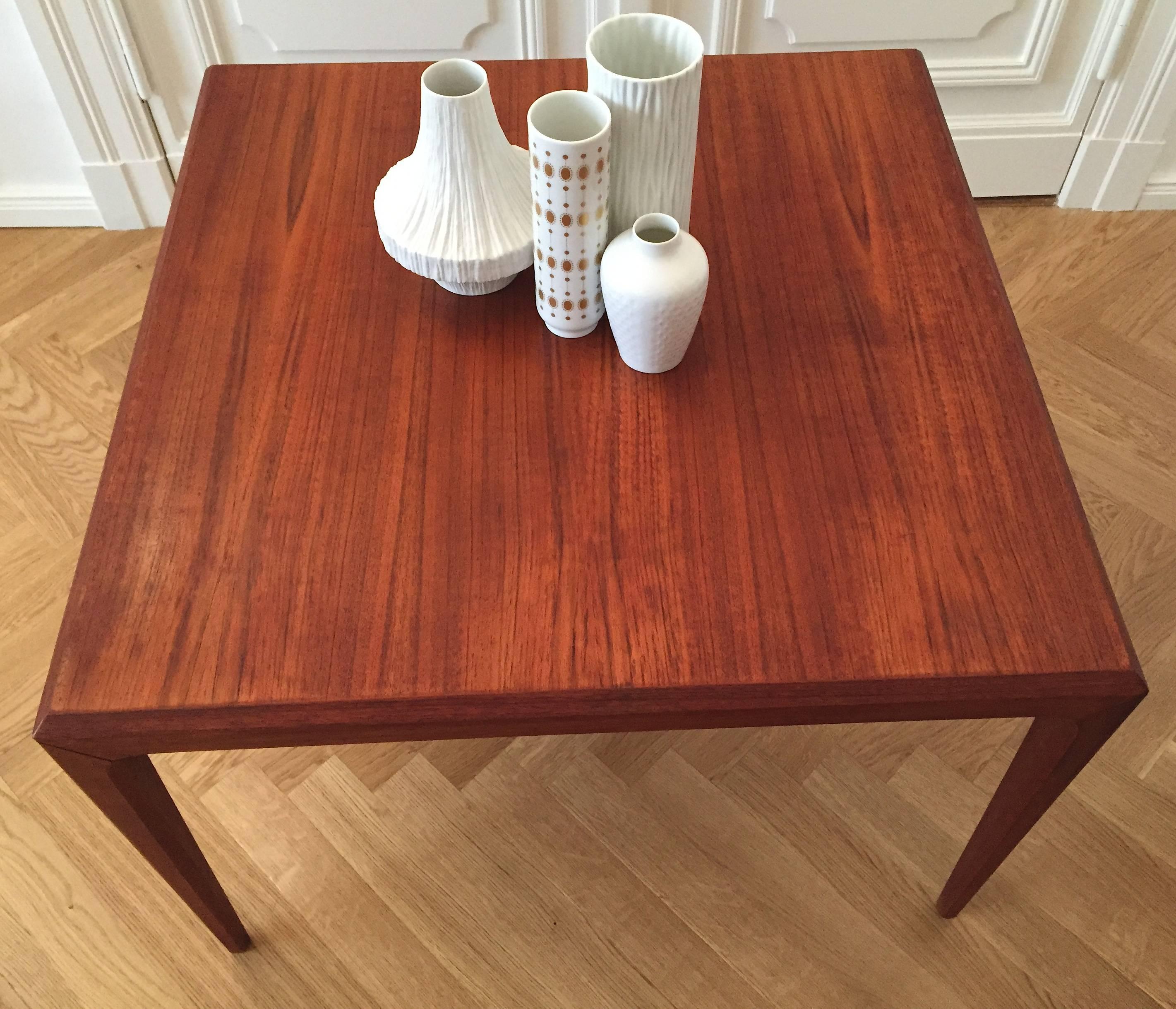 This cubic coffee table was designed by Johannes Andersen in the 1960s and has been manufactured by CFC Silkeborg in Denmark. It features a solid teak frame with a teak veneered tabletop. The top has slanted edges and the tapered legs can be