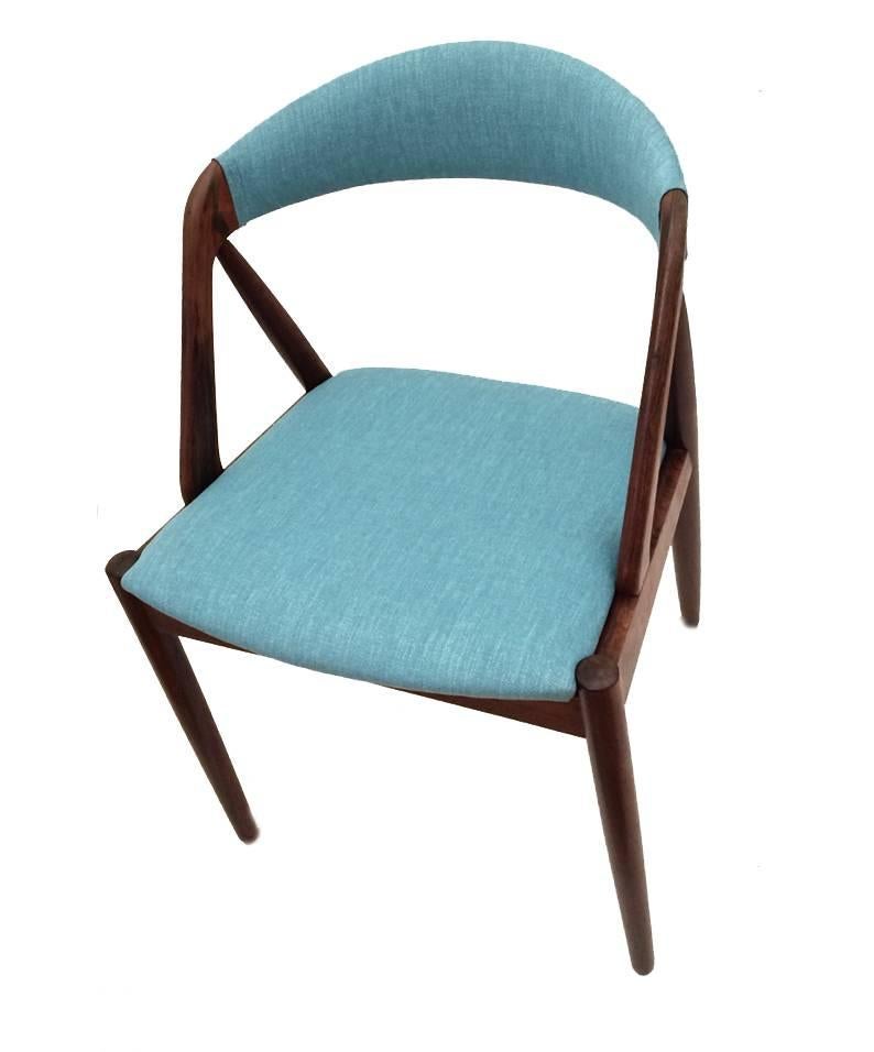 A stunning set of four desk or dining chairs model 31, designed by Kai Kristiansen. Made in Denmark by SVA Møbler. Crafted in solid Brazilian rosewood with remarkable contrasting wood grain. Seating features brand new upholstery in a caribic blue