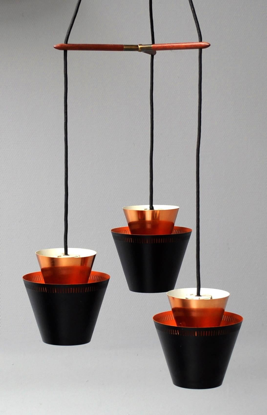 Mid-Century Fog & Mørup pendant from the 1960s, designed by Jo Hammerborg. The lamp features three trapeze lampshades, which are double layered: one in copper and one in black lacquered metal. Comes with a rosewood hanger and brass attachment