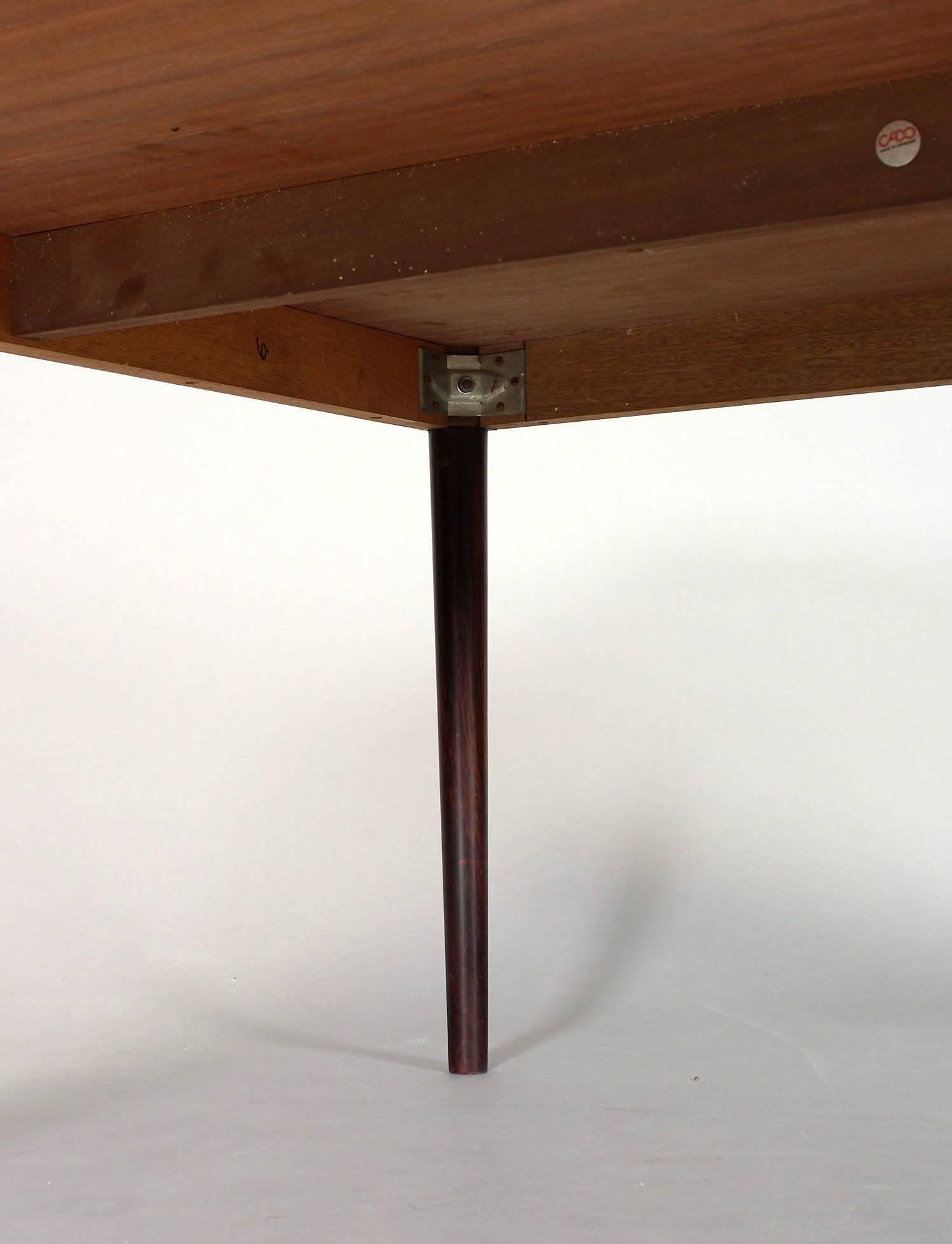 This executive desk, dining or conference table from the Diplomat series was designed by Finn Juhl and produced in the 1960s-1970s by Cado in Denmark (marked). The table features a rosewood veneer top and legs in solid rosewood, which can be screwed