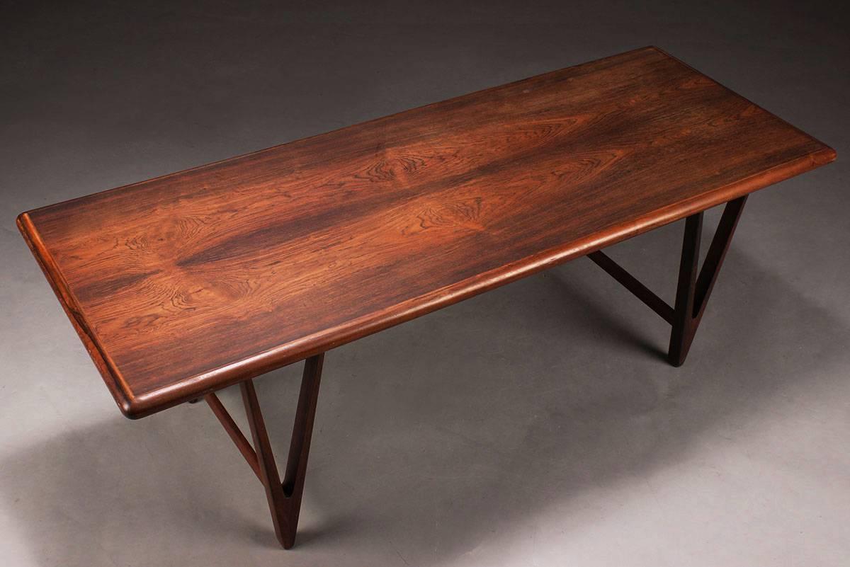 A stunning piece of Danish Mid-Century design: this coffee or lounge table is made from solid rosewood (with veneered rosewood tabletop) and features triangular legs and a rich wood grain. It was designed by E. W. Bach for Toften Møbelfabrik, and