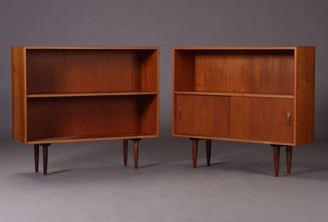 This sideboard or bookcase is made from veneered teak, on slightly conical feet. It features two sliding doors with elaborate handles. It was produced in Denmark, circa 1960.