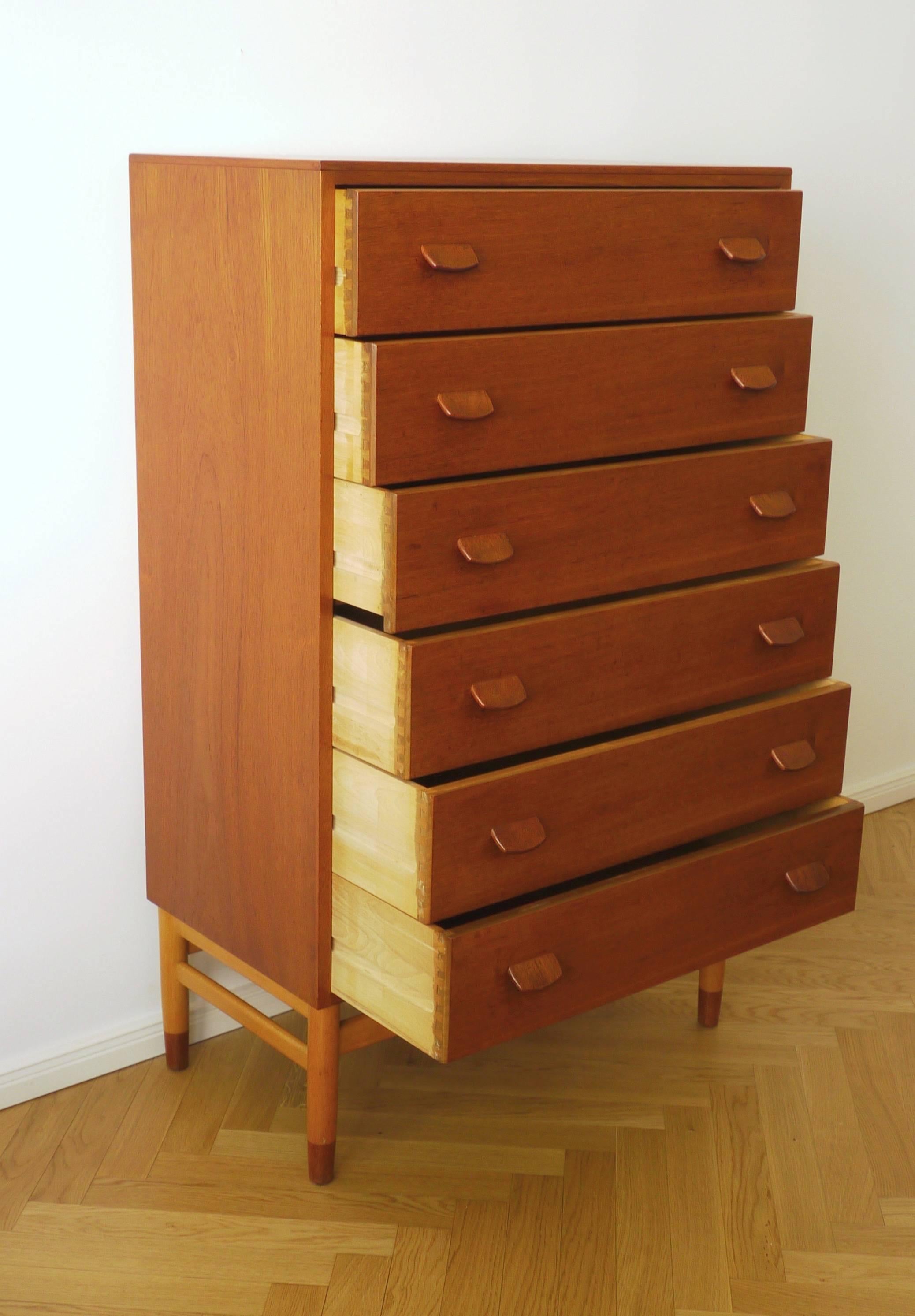 High chest of drawers, Model F17, designed by Poul M. Volther. Produced by FDB Møbelfabrik in the 1960s. The high shelf offers six drawers, it is made of teak and veneered surfaces and is standing on a base of beech legs finishing in teak.
 