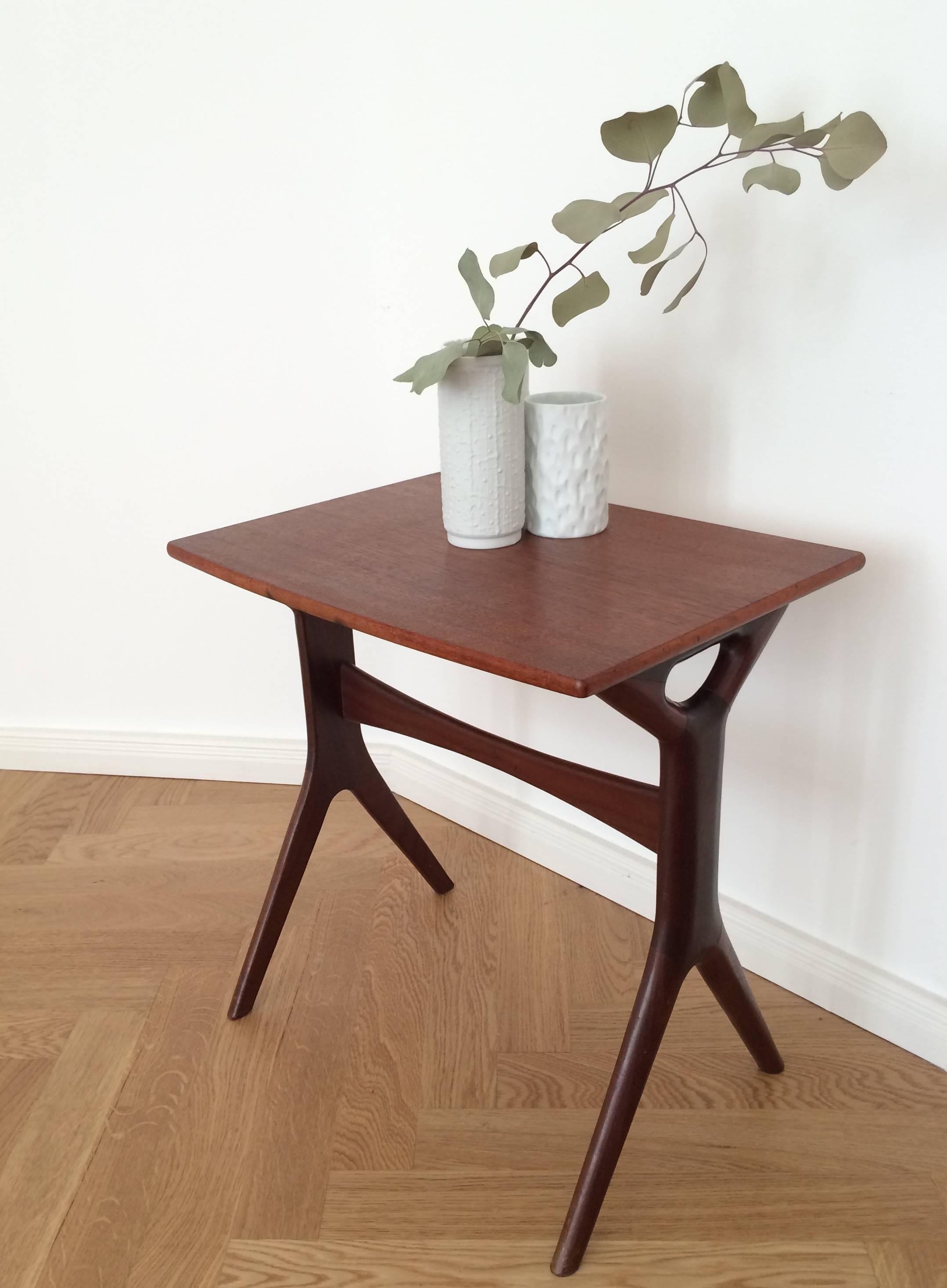 This side table was designed by the Danish designer Johannes Andersen and manufactured in Denmark by CFC Silkeborg. It consists of a rosewood veneered top and solid rosewood legs. The side table features slanted edges and cylindrical legs. Comes in