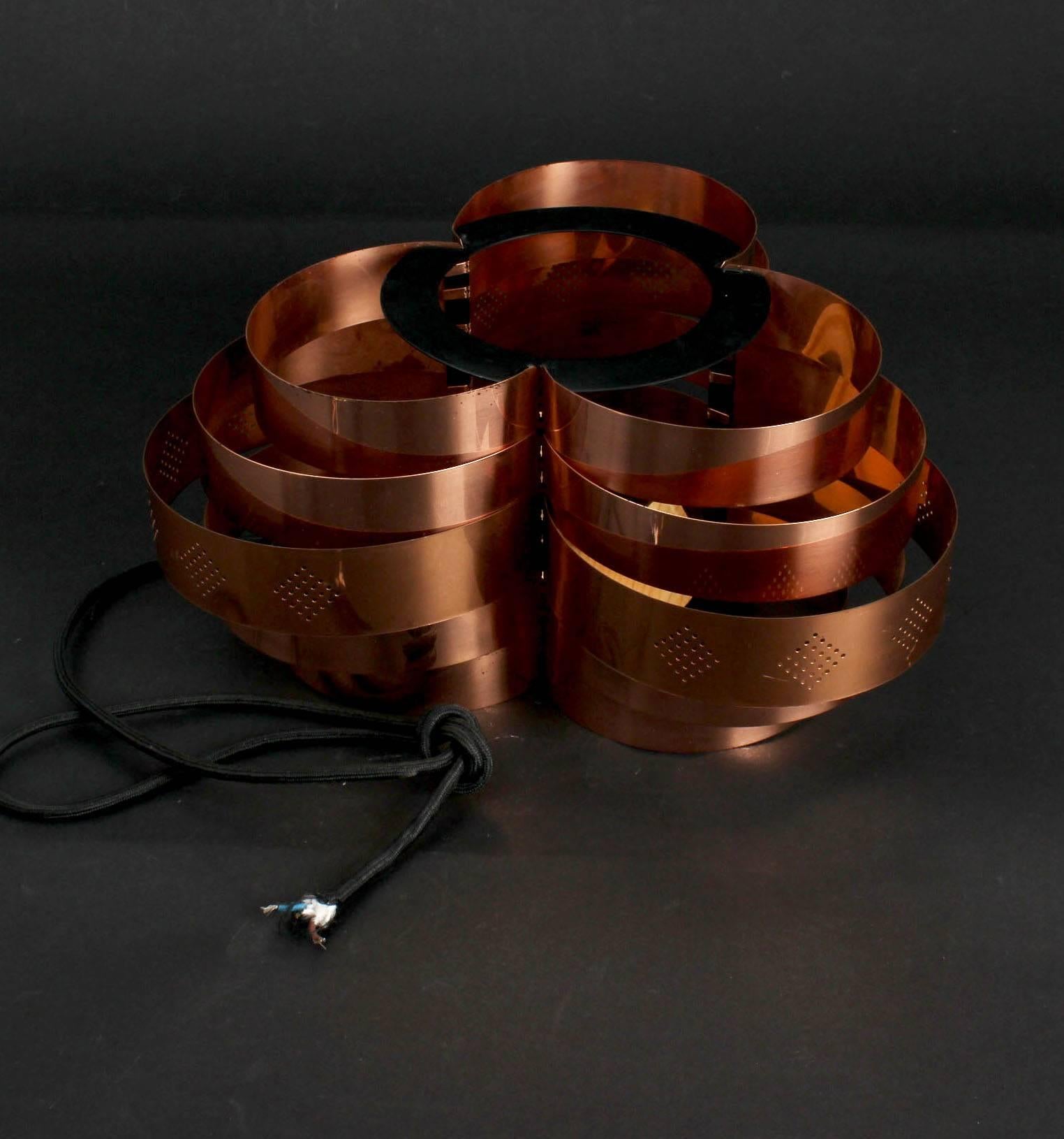This copper lamp was designed by Werner Schou and produced by Coronell Electro in the 1960s. Schou was a Danish lamp designer. The pendant lamp consists of five graded tiers of semicircular copper bands; the central strip features perforated