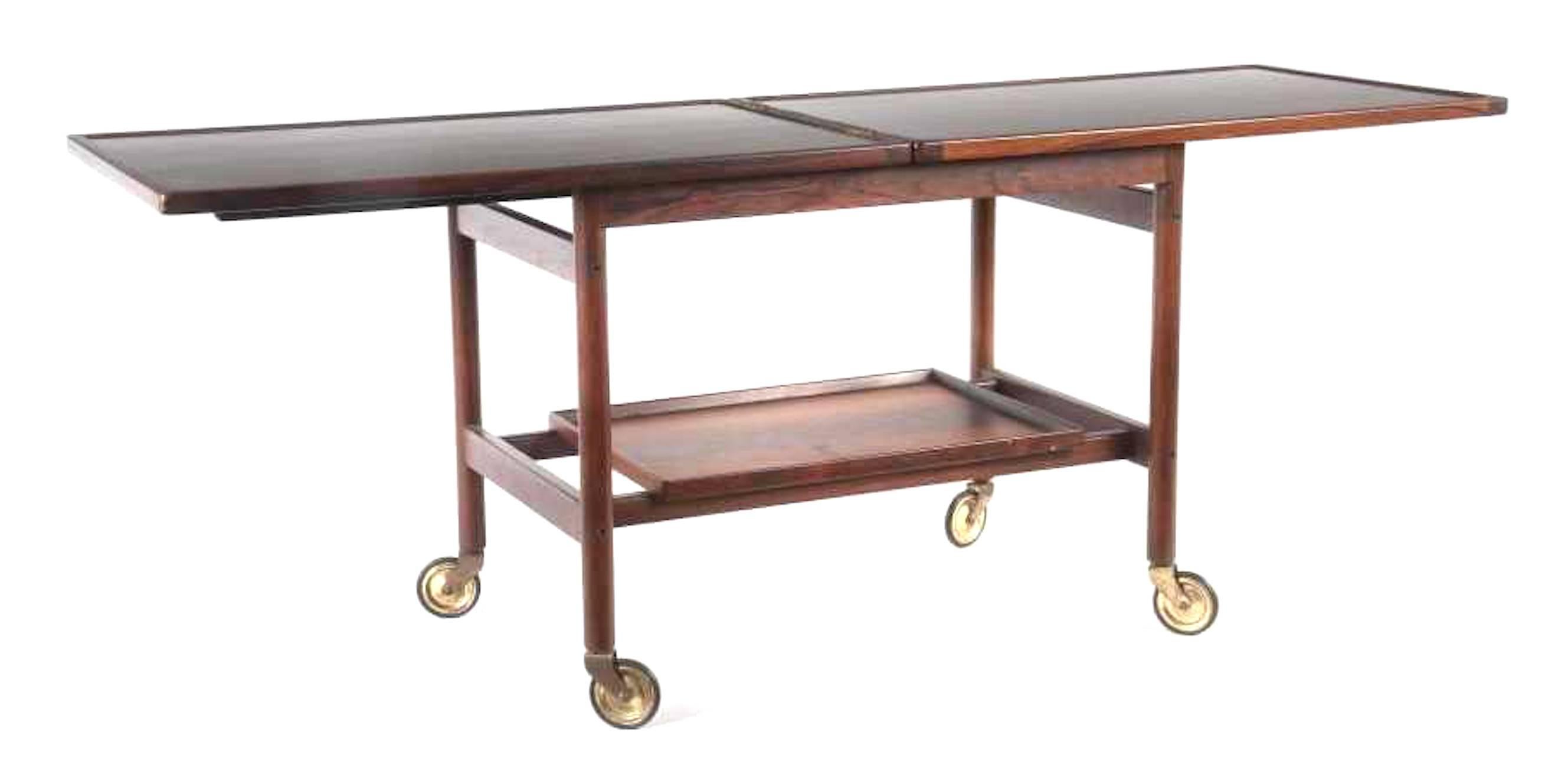 Danish bar cart designed by Kurt Ostervig in the 1960s. Made of rosewood with a remarkable wood grain. Features a rectangular shape o round wooden legs with a removable casters. The tabletop can be folded out to double width and is laminated black