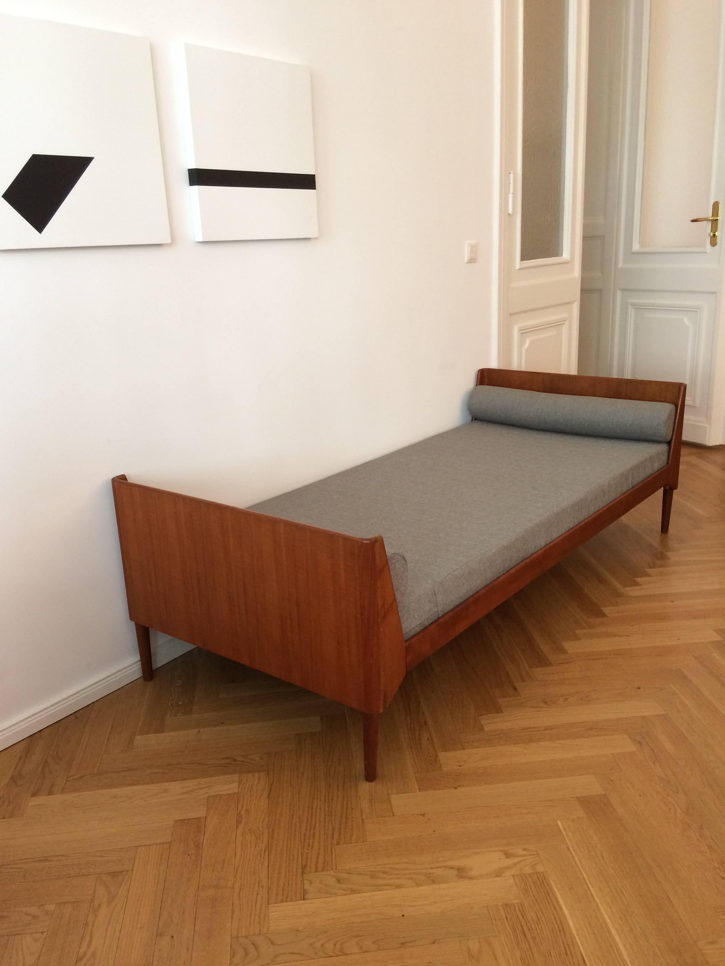 A very stylish daybed in Danish Mid Century design from the 1960s, made of solid teak wood. It features round edges and comes in original lath floor and a brand new upholstery in grey. Measurements of mattress is approximately 190 x 84 x 10 cm.
