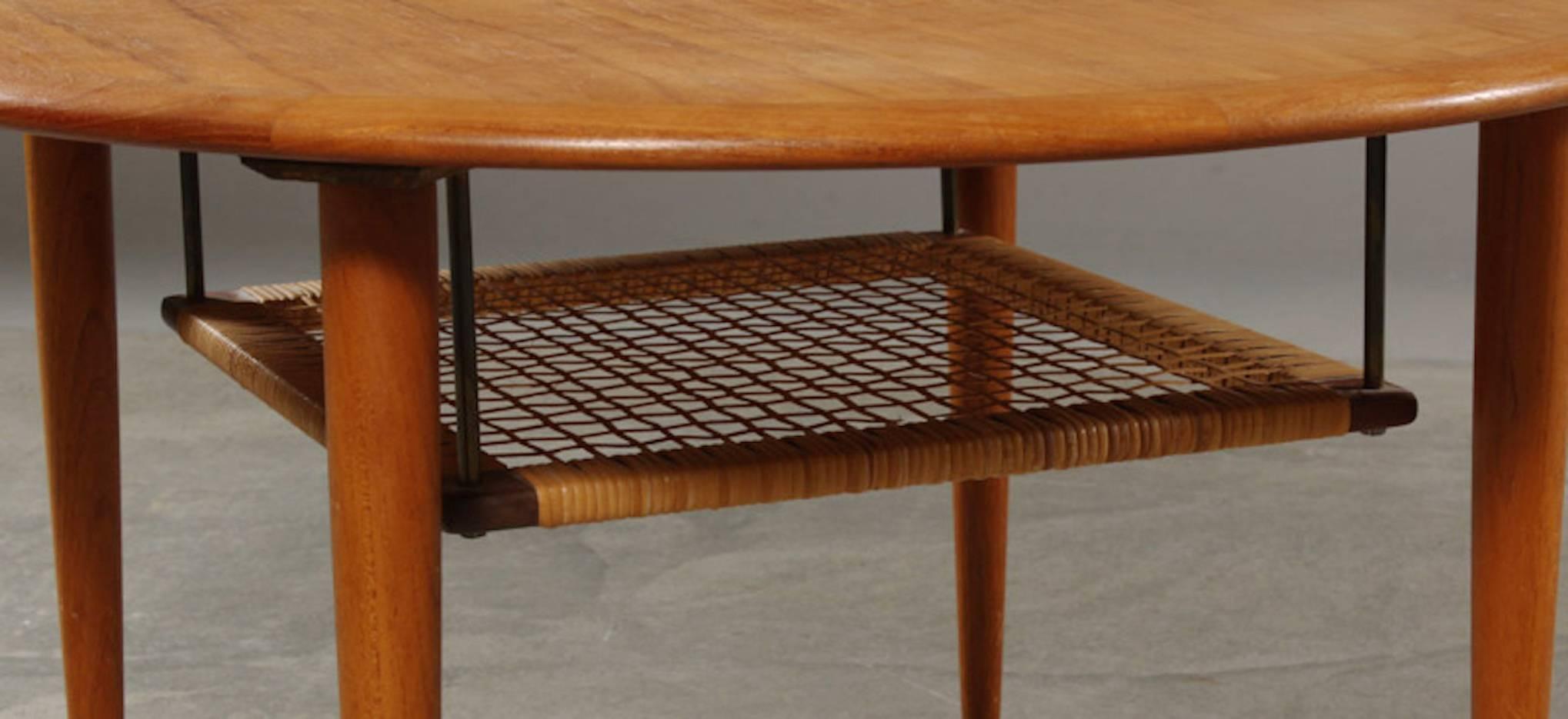 Designed by Johannes Andersen and manufactured by C F Christiansen, Denmark, circa 1960. The table is constructed of beautifully Teak which is set off with a wide darker band of wood around the outside edge. The round, tapering legs end in brass
