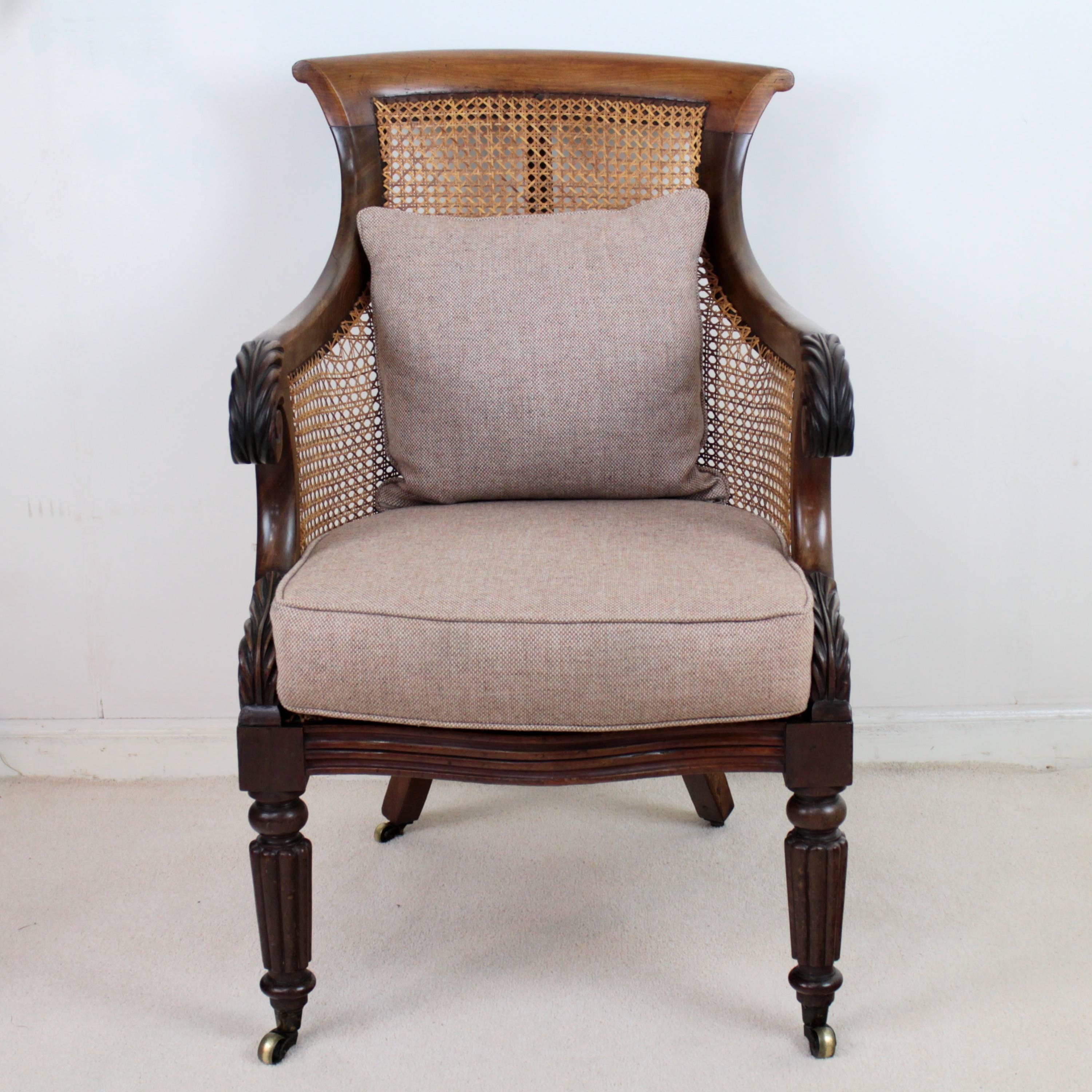 Regency period mahogany and cane-filled library armchair. With acanthus carved scroll arms and a serpentine reeded front rail it stands on turned and reeded front legs in the typical Gillows style with square tapering outsplayed legs to the rear,