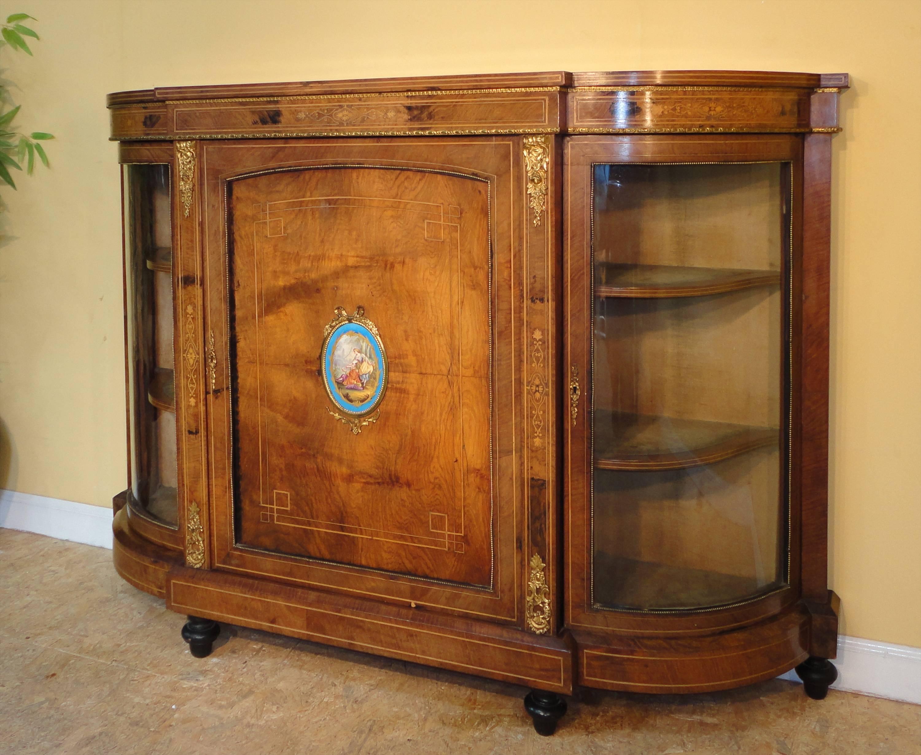 This is an attractive mid-Victorian ormolu-mounted, burr walnut and boxwood inlaid credenza dating to circa 1870. It has a breakfront top with a delicately inlaid and ormolu edged frieze, the central panelled cupboard door is centred with a