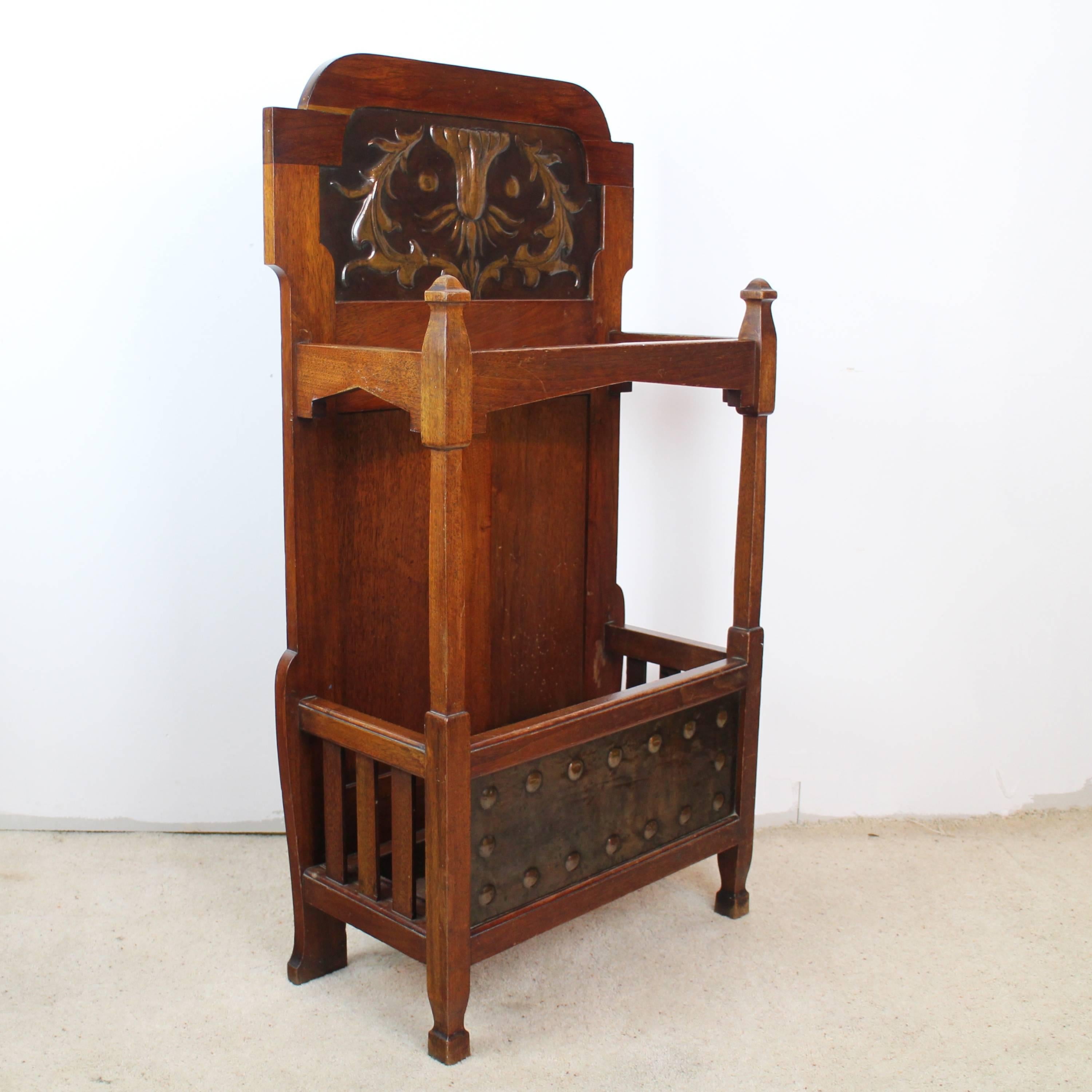 An Arts & Crafts walnut stick or hall stand by Shapland & Petter of Barnstaple and dating to circa 1905, with stylized floral copper panel to the top and copper panel with roundels to the bottom, original drip tray and patina, impressed number to