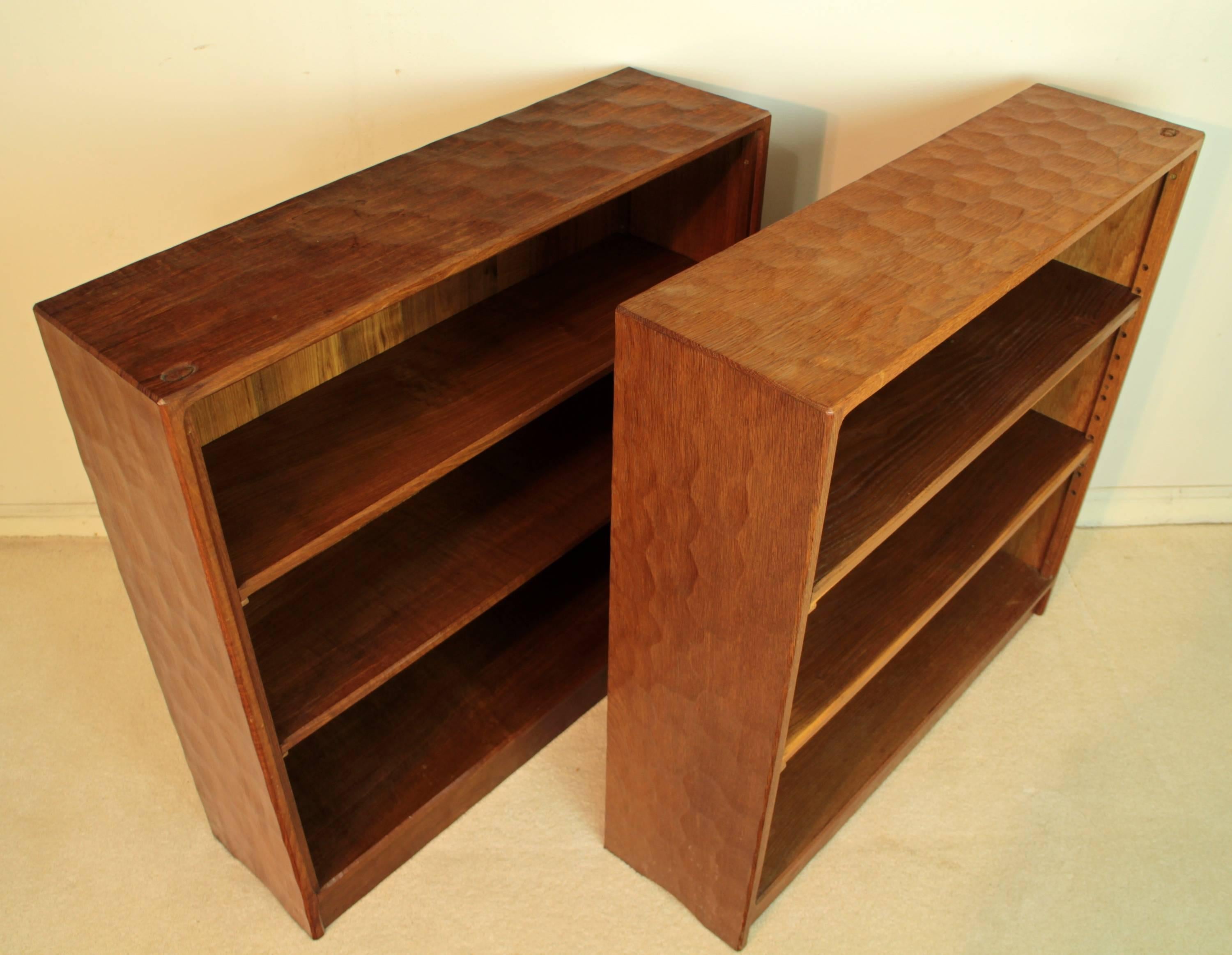 A rare pair of adzed oak open bookcases by Alan “Acornman” Grainger and dating to circa 1970. The adzed top and sides give a distinctive handcrafted wavy pattern to the surface and each has two adjustable shelves and carved acorn signature trademark
