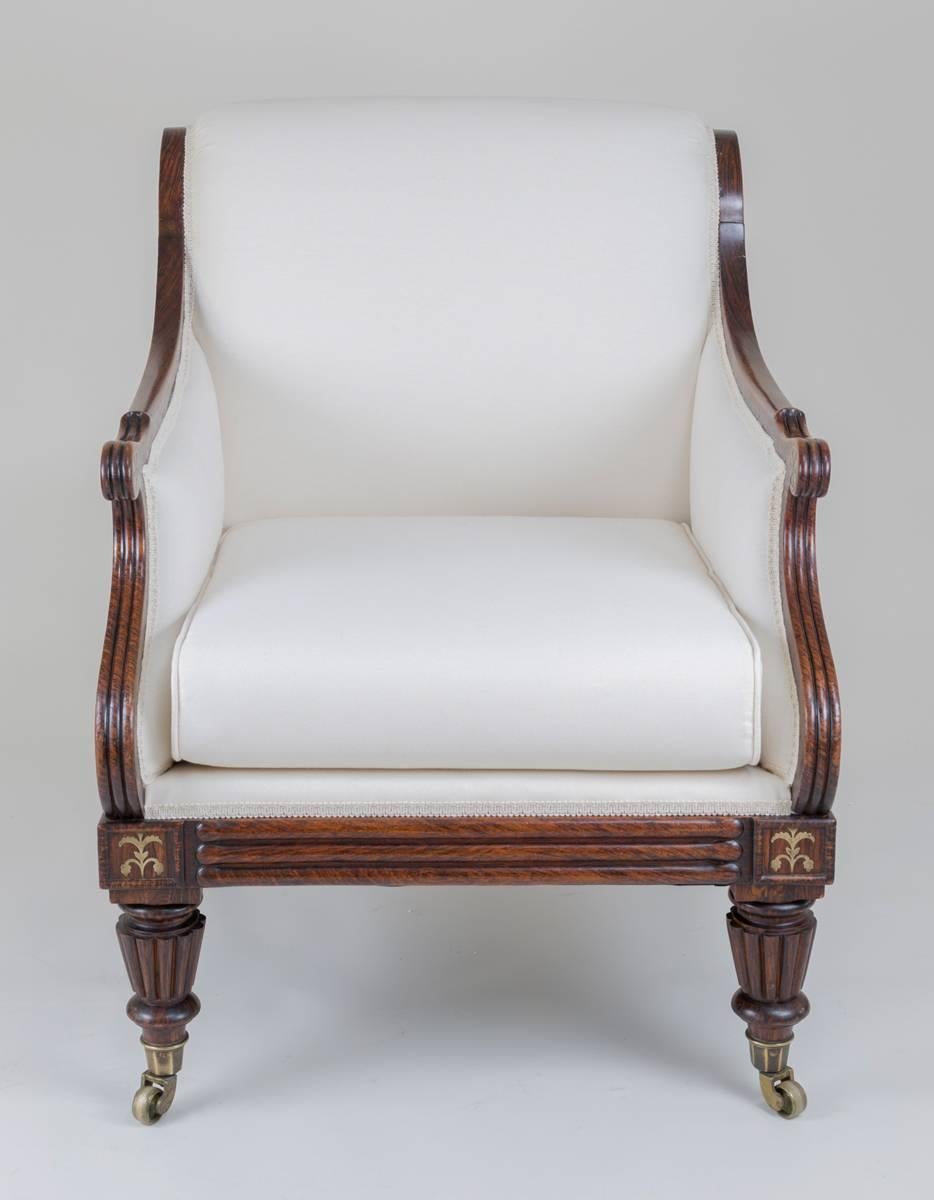 Fine early Regency simulated rosewood and brass inlaid library armchair, the out-scrolled back top and hand rests inlaid with brass rondel shapes, the molded apron front and sides also inlaid with brass motifs, supported on carved and reeded legs