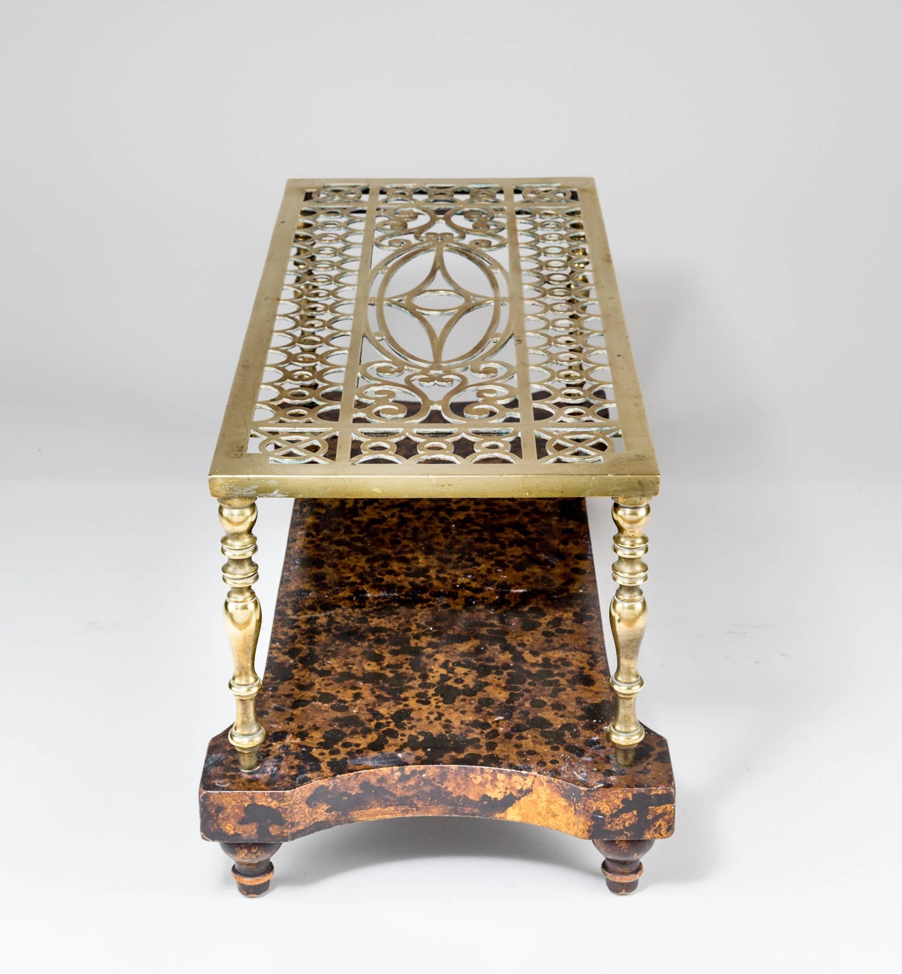 Antique rectangular low coffee or end table consisting of a cast brass trivet on a painted faux tortoiseshell base. The top of the trivet is decorated with pierced ovals, circles and C-scroll designs, the legs are of balusters shapes.