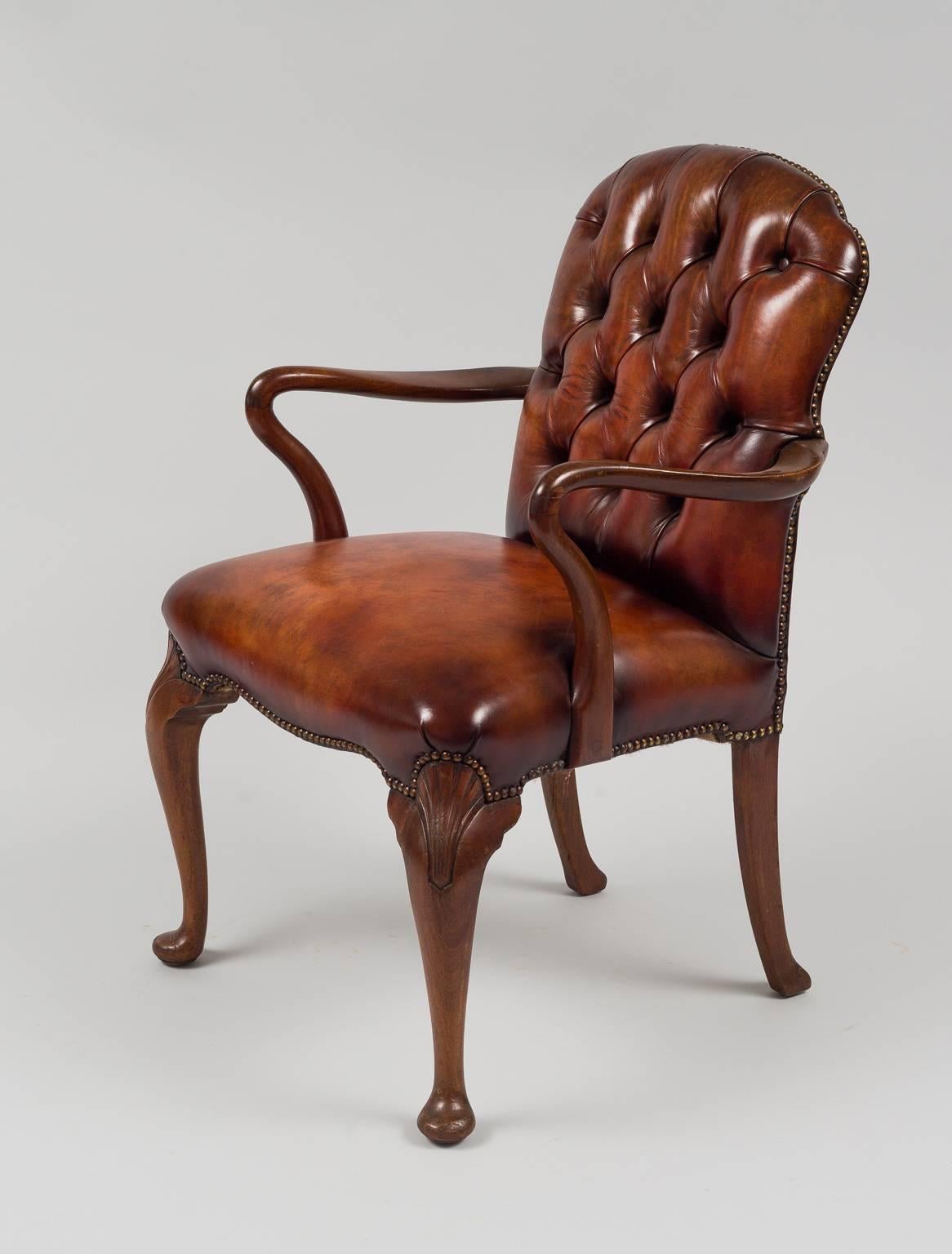 Mahogany frame with leather buttoned back and tight seat, cabriole legs with shell carving on knees ending in pad feet. Upholstered in cognac-colored leather with brass nailheads.