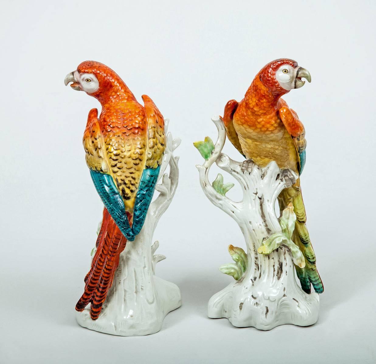 Pair of porcelain parrots perched on a tree stump decorated in brightly colored enamels of orange, yellow, teal and red with black markings. No manufacturers mark on the bottom, but most likely German.