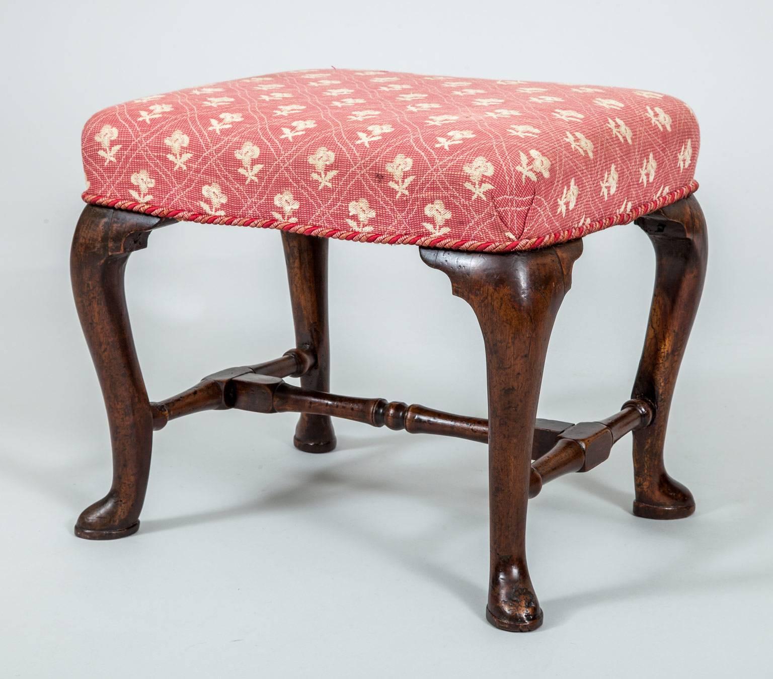 Antique Queen Anne walnut stool with cabriole legs joined by carved and turned H-shaped stretchers raised on pad feet.