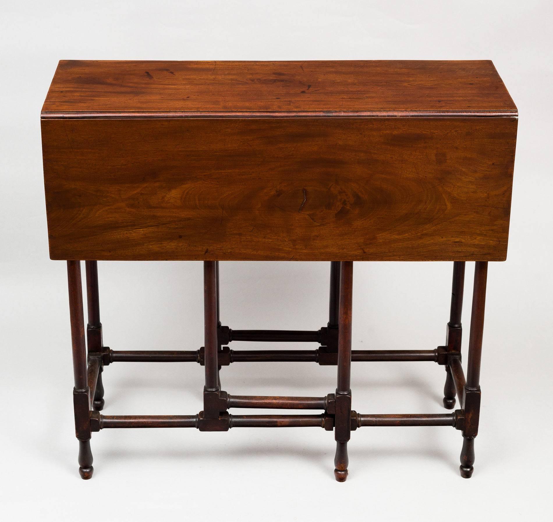 Georgian mahogany spider leg table having a rectangular top with two drop leaves that are supported by slender turned gate legs and are joined by carved and turned stretchers. It has a rich patina and color.