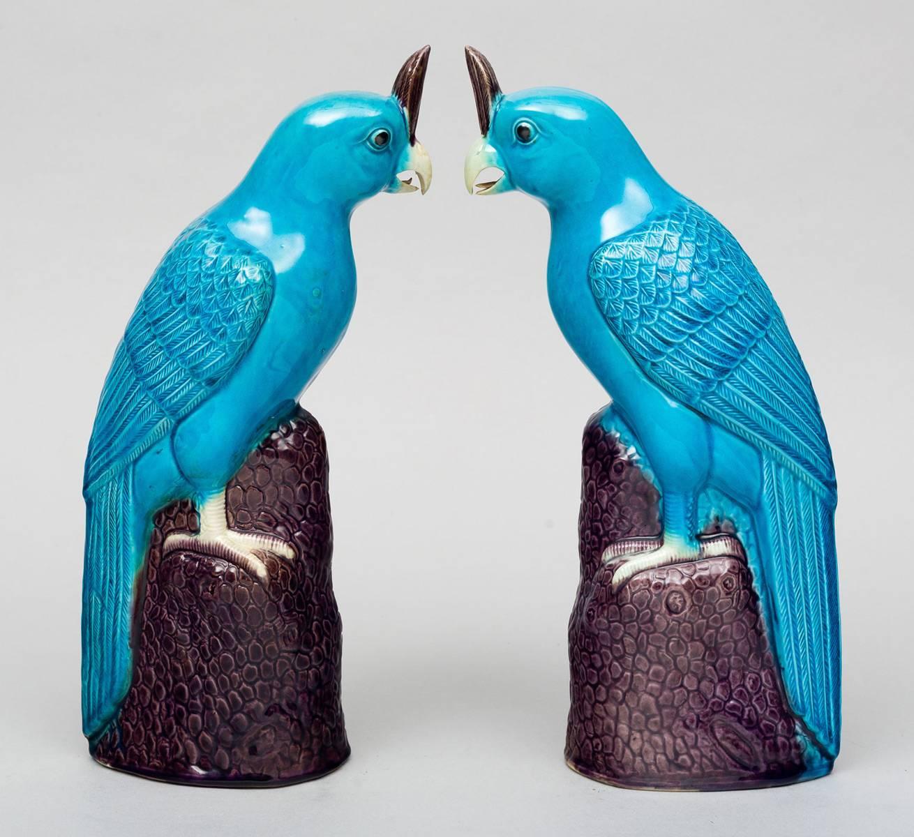 Large pair of Chinese turquoise glazed models of cockatoos with purple head feathers, well defined wing and tail feathers, perched on a tall purple tree stump.