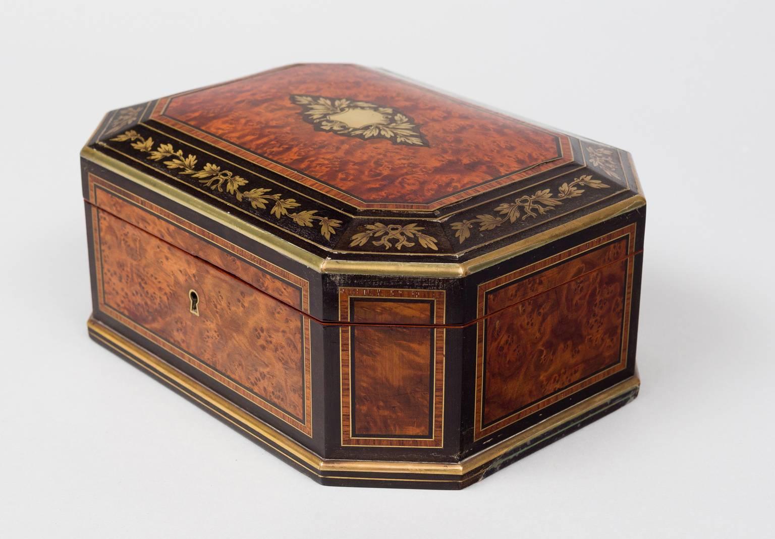 Early Victorian octagonal-shaped burr walnut, ebonized and brass inlaid jewelry box, the top inlaid with a brass shield and sprays of leaves on an ebony background, the top border set with brass inlaid leafy stems, the sides with walnut panels