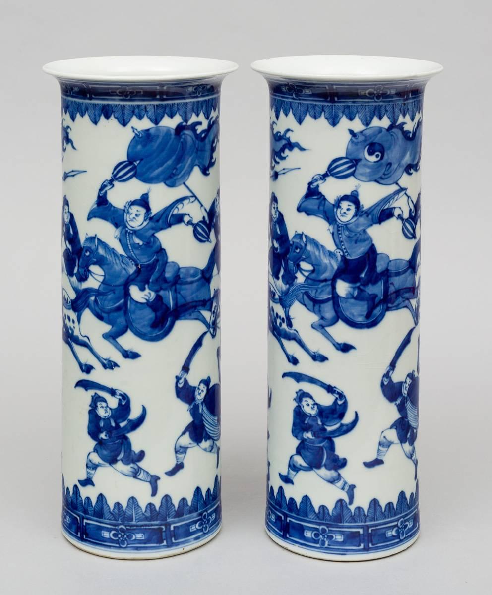Pair of Chinese porcelain blue and white tubular open vases with a flared neck decorated with men on horseback competing in a battle scene, men at bottom wielding swords. Borders at top and bottom are leaf patterns.