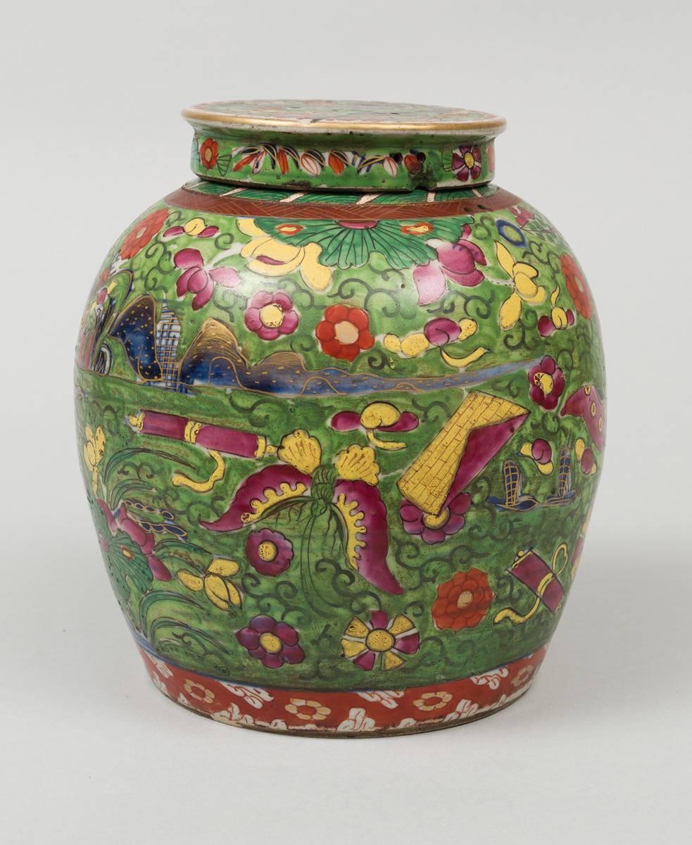 Chinese clobbered squat jar and cover, decorated with exotic houses, mountains, flowers, butterfly and a river in vibrant colors and gilding on a green background. It retains its original cover. Tiny holes in the cover and on the shoulder of the jar