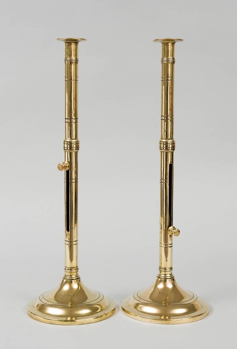 Very tall heavy cast brass pulpit candlesticks decorated with four scribe lines near the top, followed by four bands of two lines. There is one raised section joining the upper and lower section. The push-ups or ejectors are in the lower section.