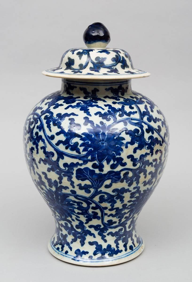 Large Chinese Qing period porcelain blue and white baluster-shaped vase with lid and knob, decorated with chrysanthemums and lotus amid continuous scrolling vines.