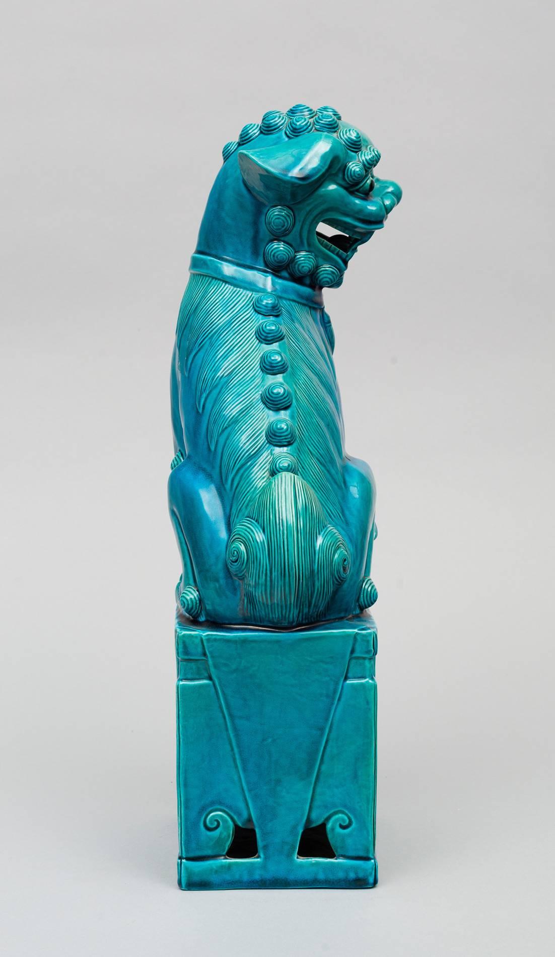 Large Chinese porcelain glazed turquoise female Foo dog sitting on a square plinth base.