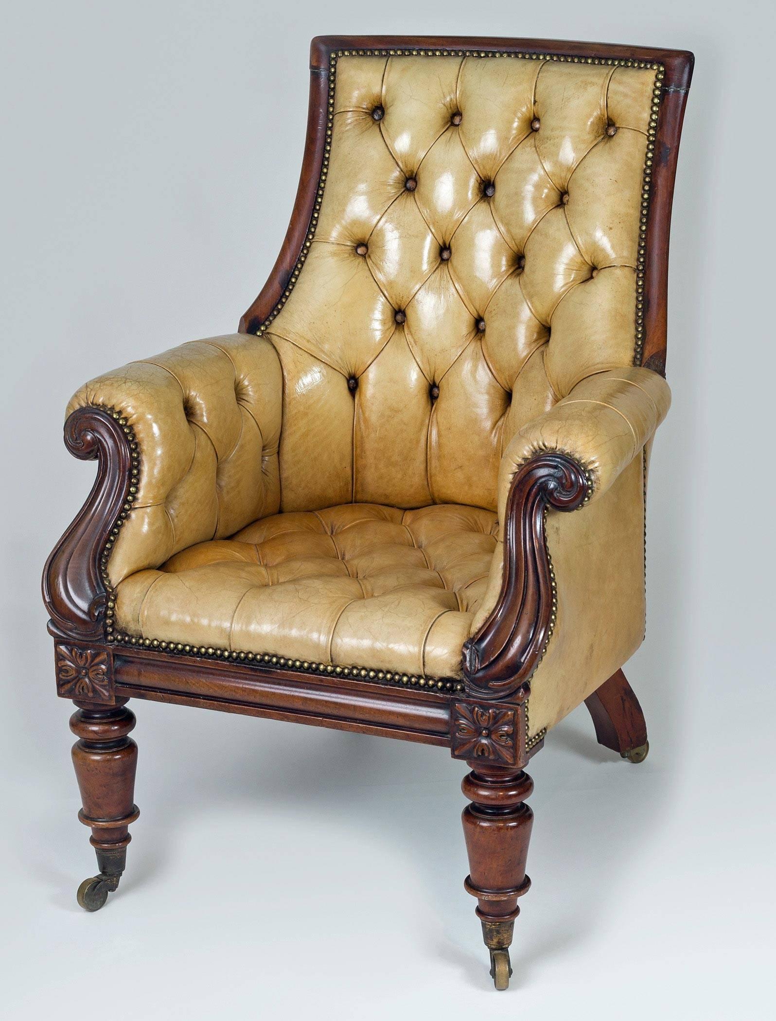 Important late Regency mahogany framed and leather library armchair with high back, outward scrolled arms, down swept carved arm supports above a deep mahogany frieze with carved acanthus leaf blocks, raised on ring turned legs on brass casters. The