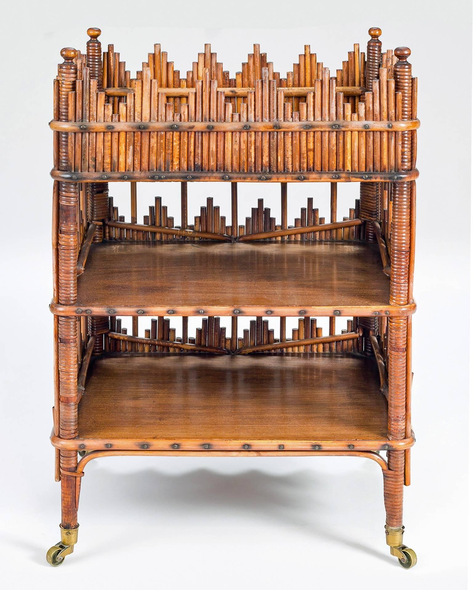 Unusual and charming bamboo three-tiered side or end table, the galleries made of bamboo pieces in diamond patterns, raised on casters.
