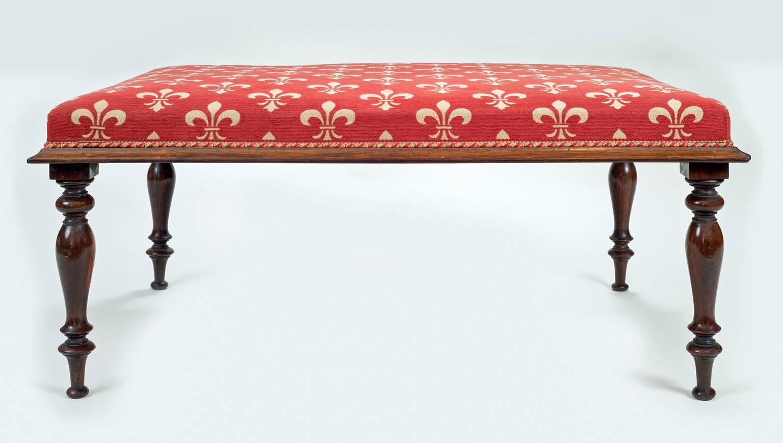 Regency bench with rosewood frame on turned legs. Upholstered in Brunschwig and Fils fabric decorated with fleur-de-lis on red background.