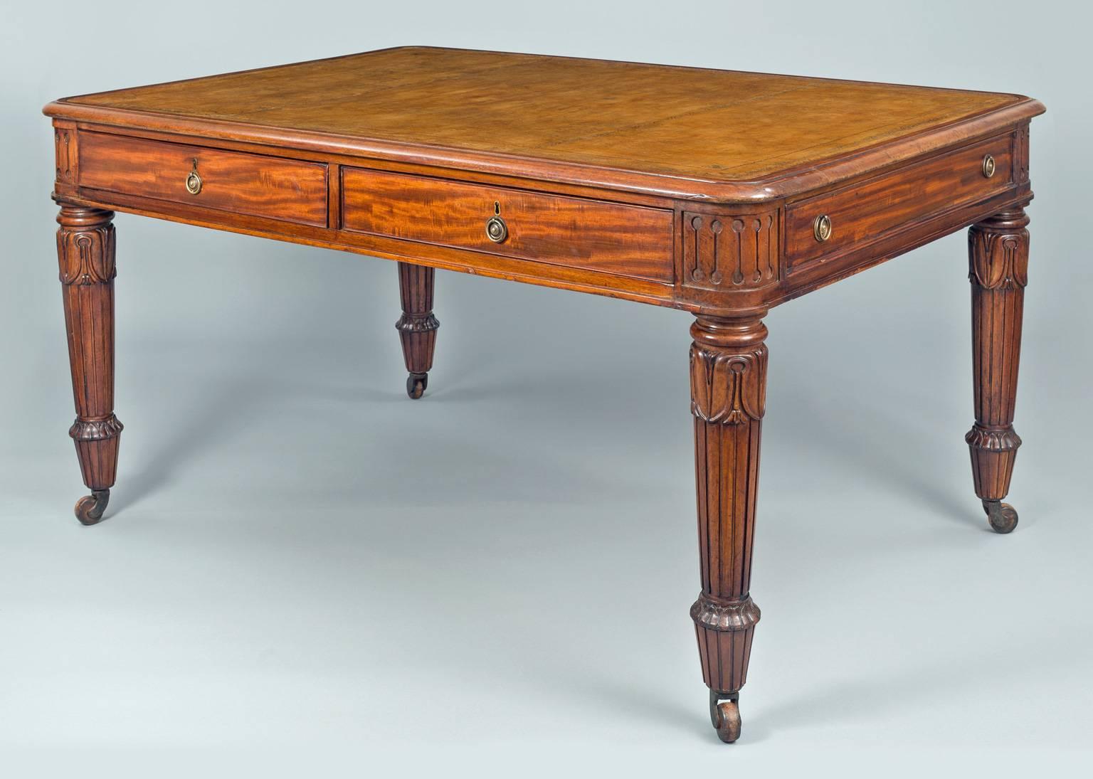 Antique late Regency mahogany partners writing table, the top with golden brown leather insert with gilt tooling, two drawers on each side with brass ring pulls, frieze corners are carved, top of leg with ring turning above acanthus leaf carving,