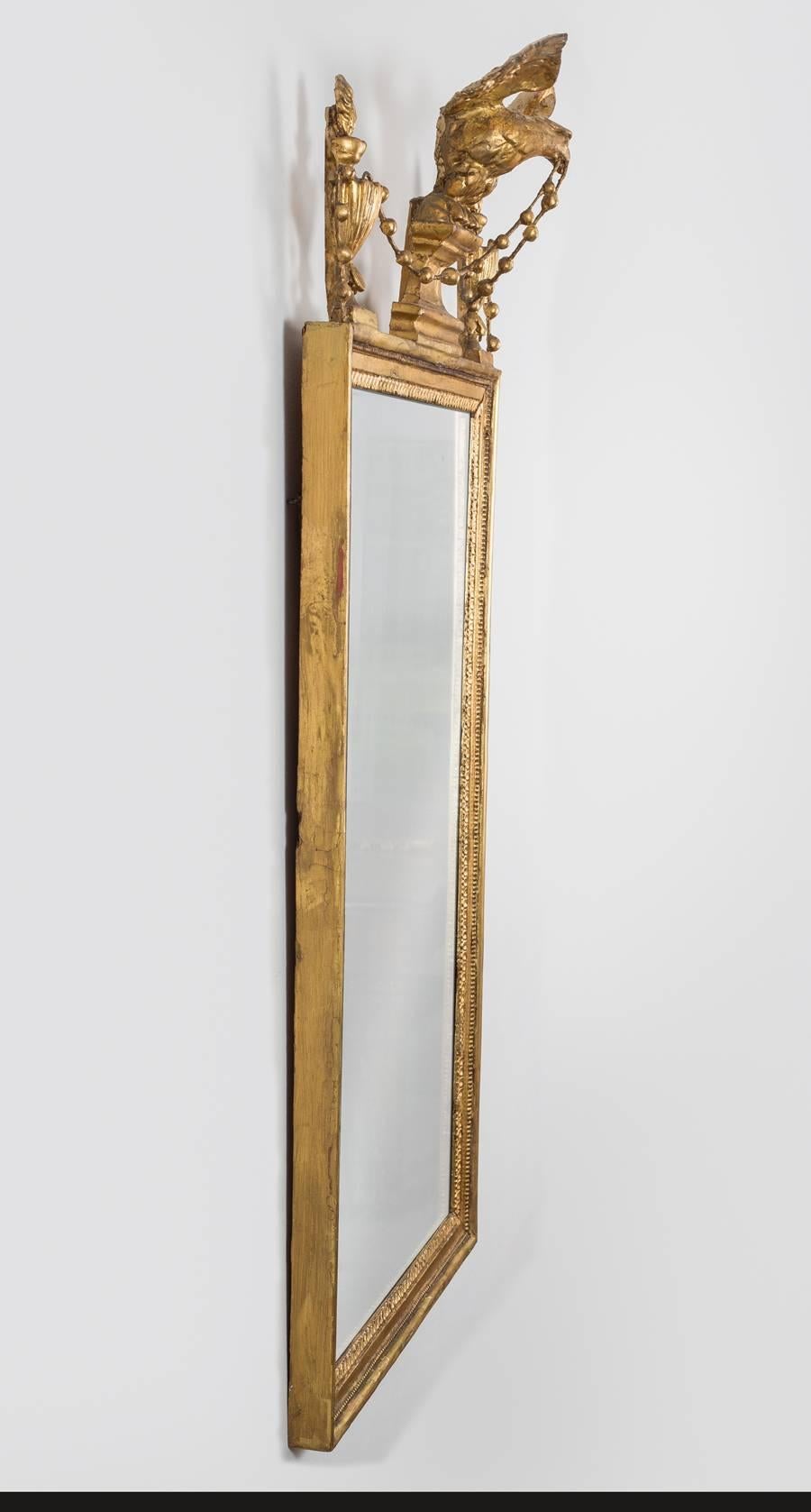 Sheraton period neoclassical giltwood pier mirror, the rectangular mirror plate within a molded and beaded frame edged with egg and dart design, surmounted and centered by a winged eagle perched on a shaped plinth, flanked by flaming urns and joined