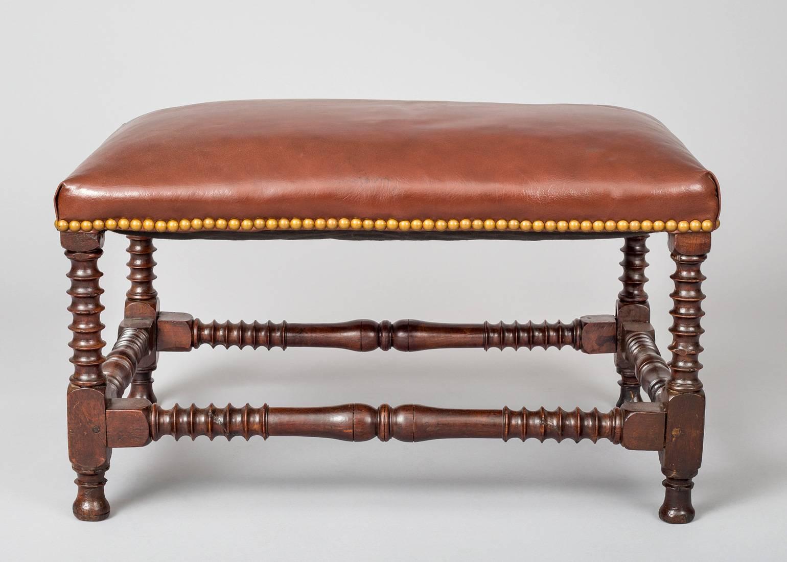 Italian walnut stool with spiral and vase turnings on the legs and stretchers.  Upholstered in brown leather with brass nail heads.