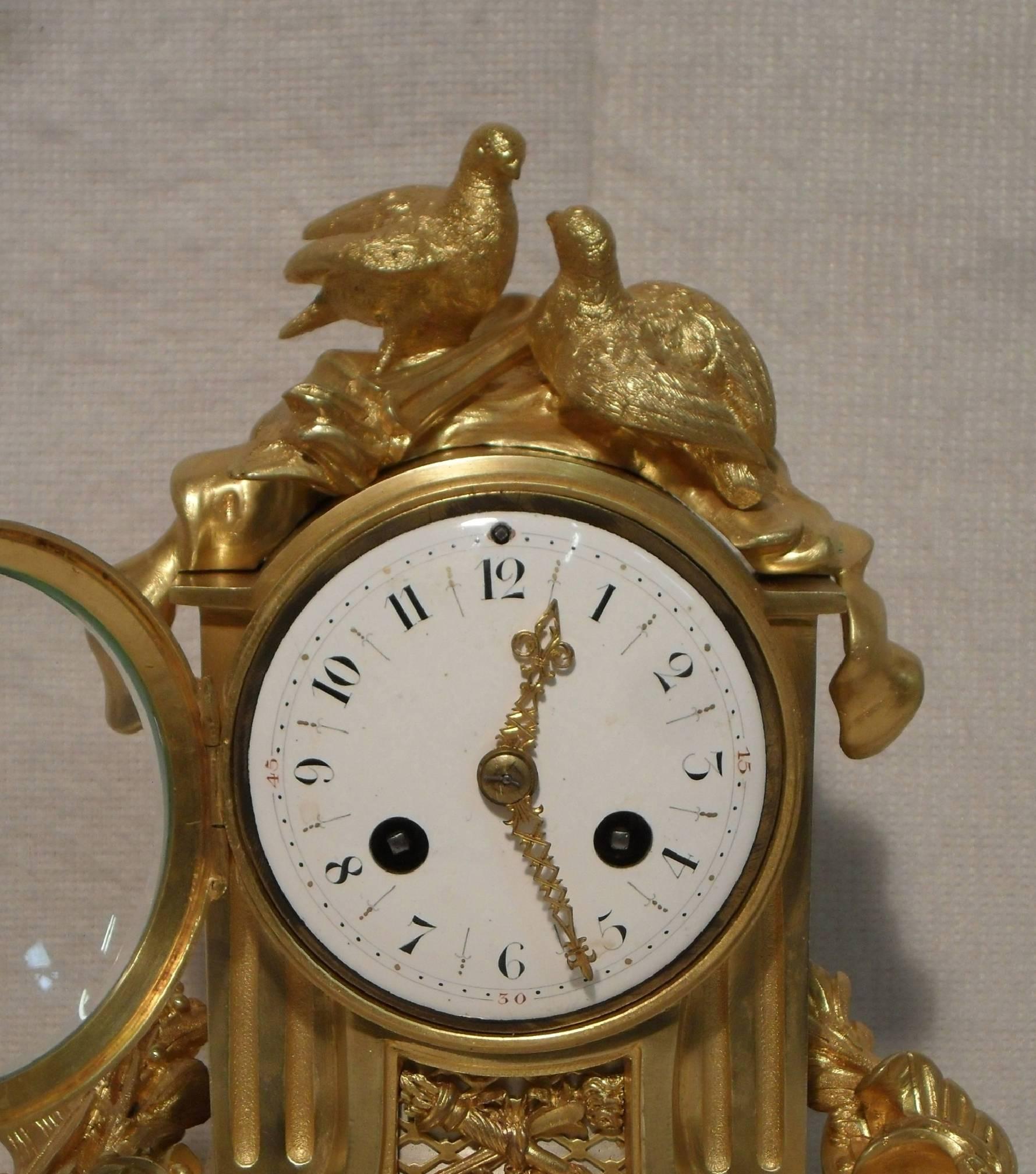 An extremely good quality French bronze gilt ormolu and marble mantel clock with pierced frets, musical instruments and a soldiers helmet and shield surmounted by two doves. The clock has a white enamel dial with a French eight day movement which