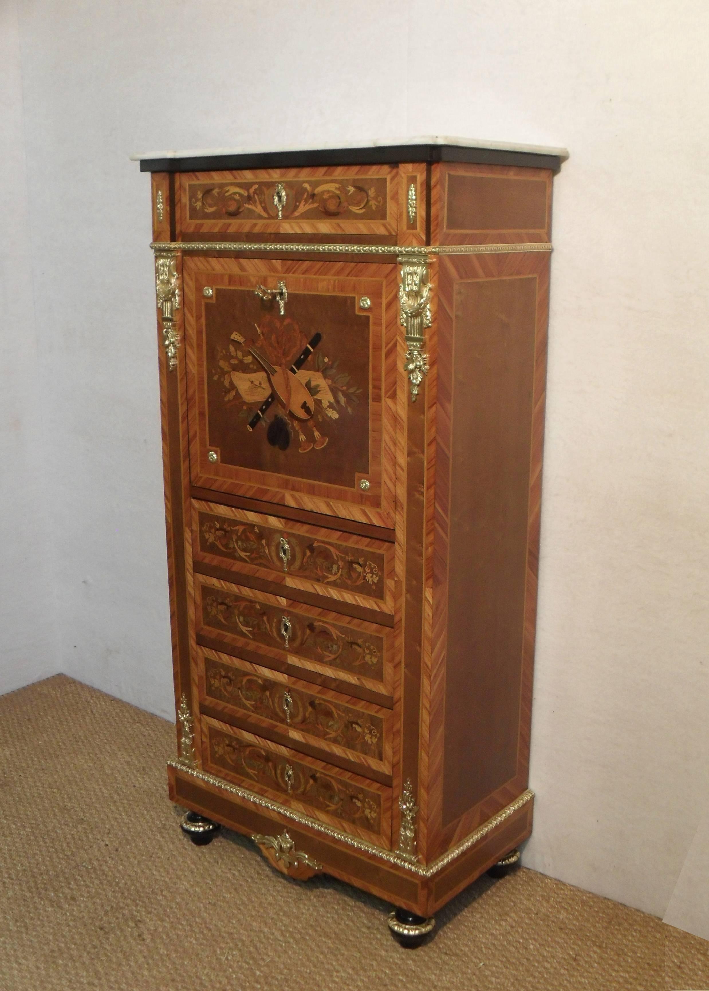 An exceptional quality French marquetry inlaid escritoire writing cabinet. The fall is beautifully inlaid with musical instruments and the drawers with a scroll leaf design made up of various coloured woods. The cabinet has dyed bird's-eye maple