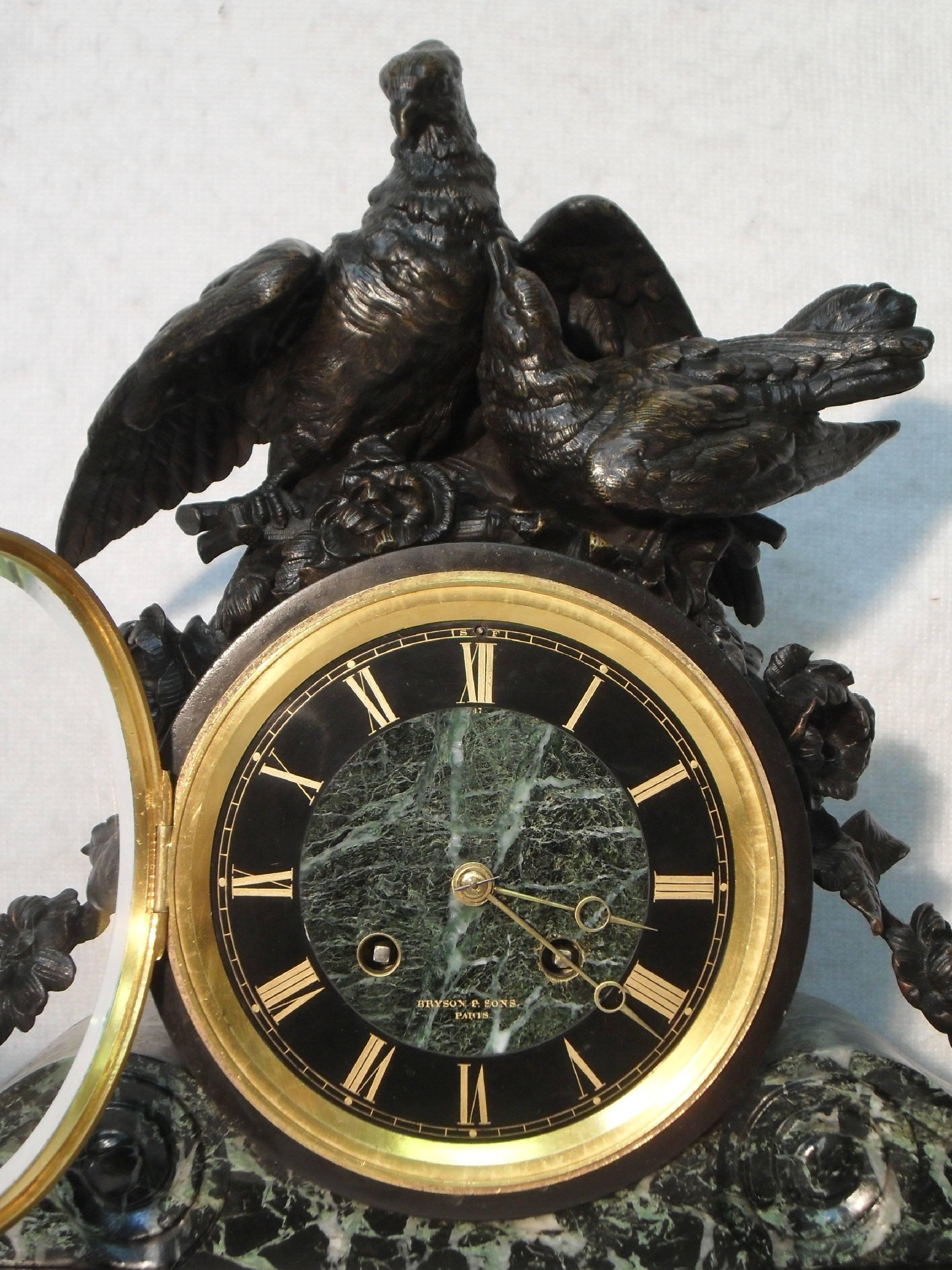 A very impressive black slate and green and white veined marble mantel clock with two bronze doves and intertwined cascading flowers stood on bronze feet. The clock dial has a marble centre with gilt numerals on a black slate background with a