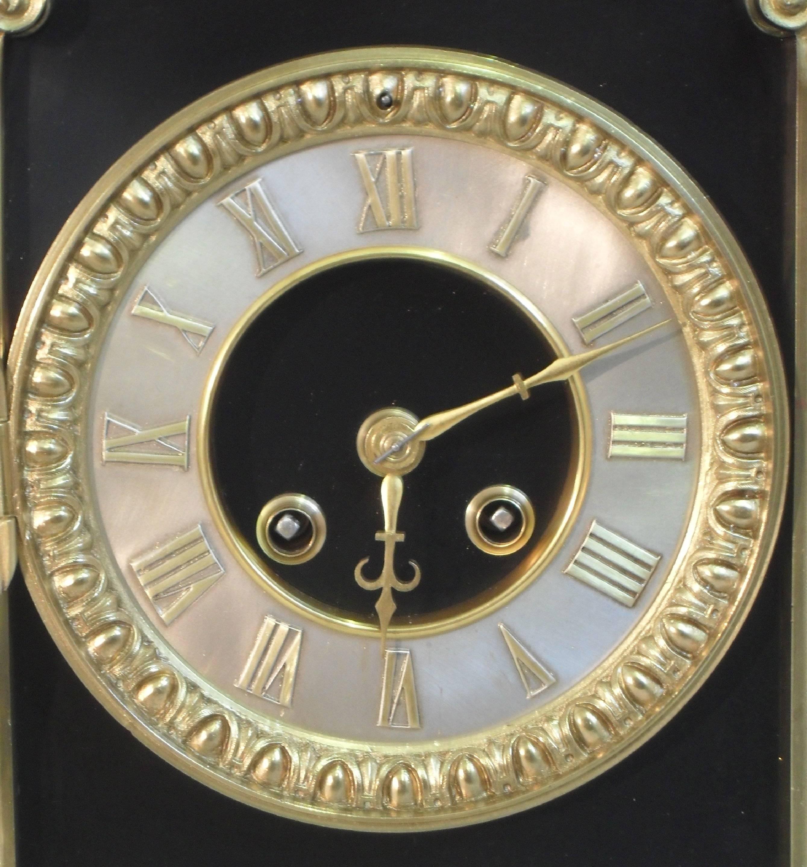 An impressive and fine quality French Belle Epoque black slate and rouge marble mantel clock with bronze gilt Corinthian columns to the font and floral decorative drop carrying handles. The clock dial has a silvered chapter central ring with egg and