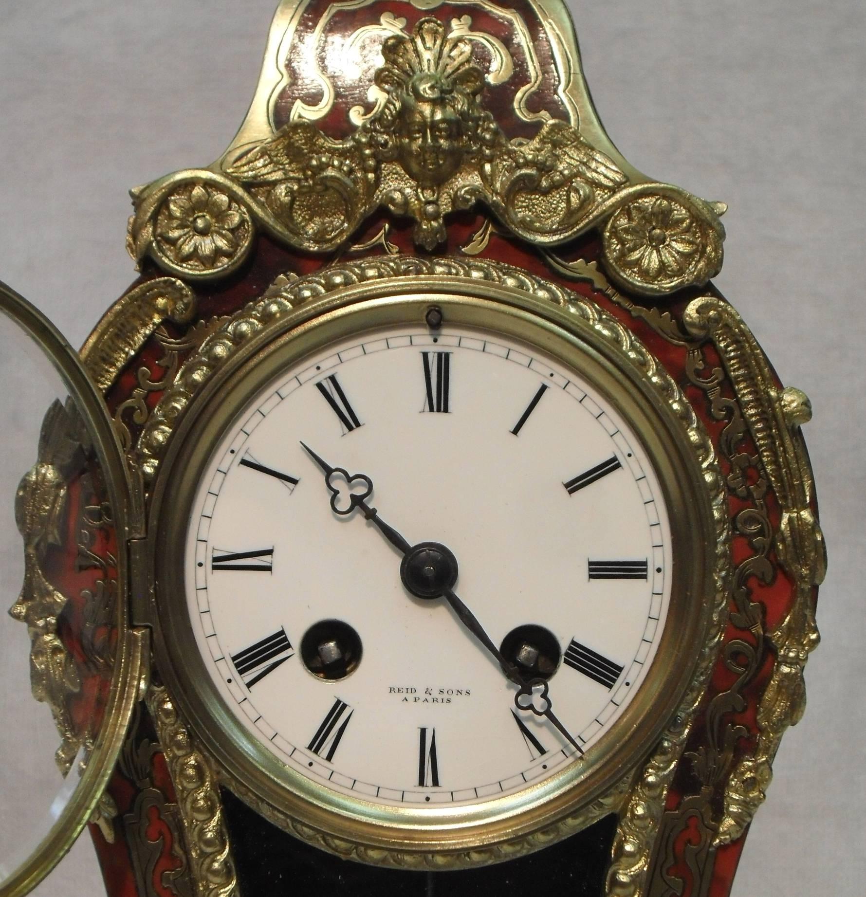A good quality French Boulle red tortoise shell and engraved brass inlaid mantel clock in the Louis XV style with ormolu mounts and pendulum viewing window. The clock has a white enamel dial with French eight day movement with outside count wheel