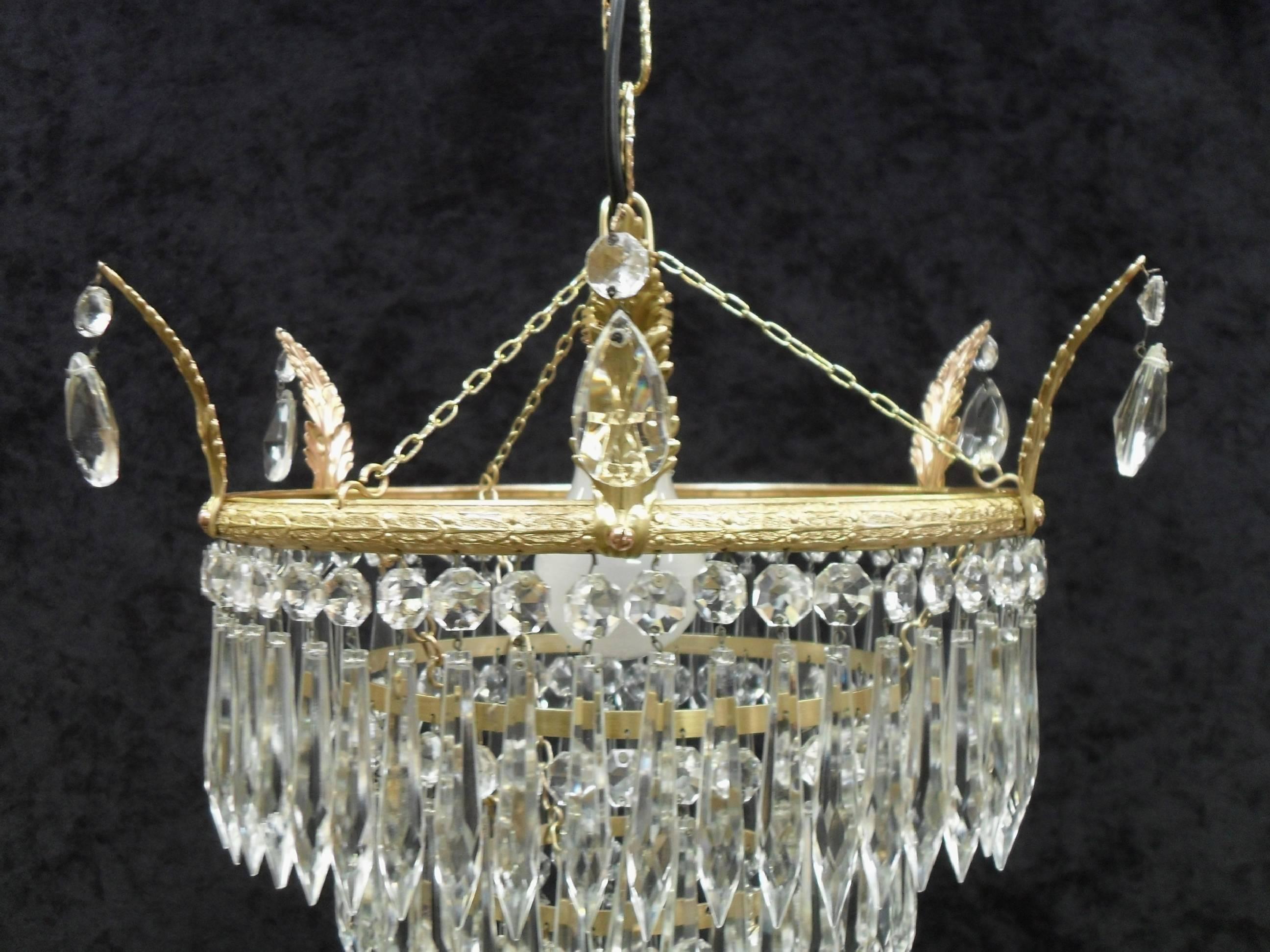 A very good quality Italian Art Deco four tier chandelier light with glass droplets and decorative brass frame with hanging leaves on a chain. The brass has been cleaned and lacquered and the light has been rewired and is in full working order.
 