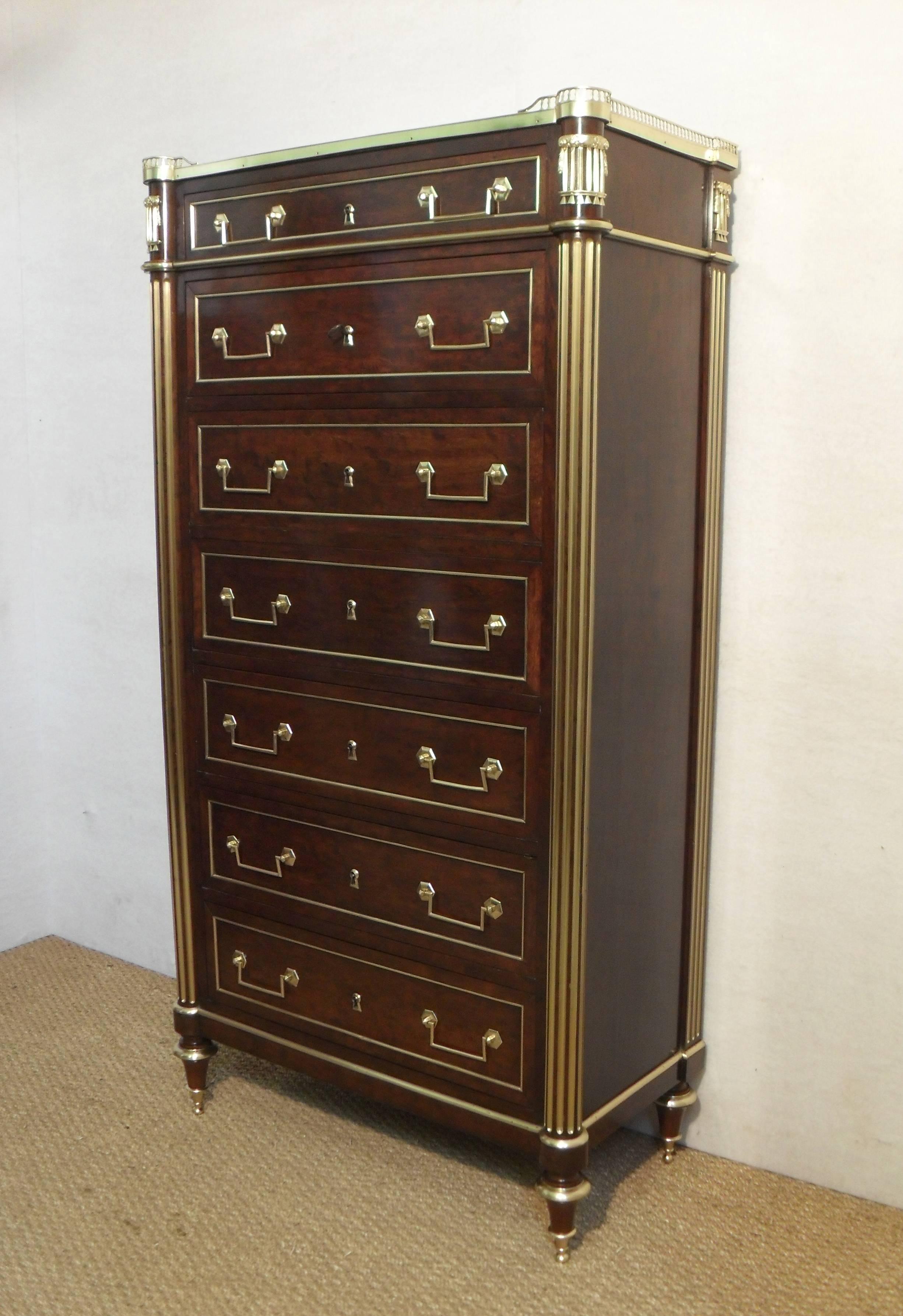 A fantastic quality French tallboy or chest of drawers with beautiful plum pudding figured mahogany veneers. The chest has four fluted brass inlaid columns and turned vase shaped feet. The drawer fronts have inset panels with quarter brass mouldings