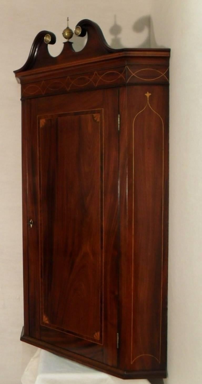 A very fine example of a quality Georgian flat fronted corner cupboard still retaining its original swan neck pediment and inlaid with boxwood stringing and satinwood fan inlays to the corners of the door.