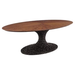 Mesa de comedor ovalada de estilo escultural con tablero de nogal y base de fundición con acabado lacado texturizado